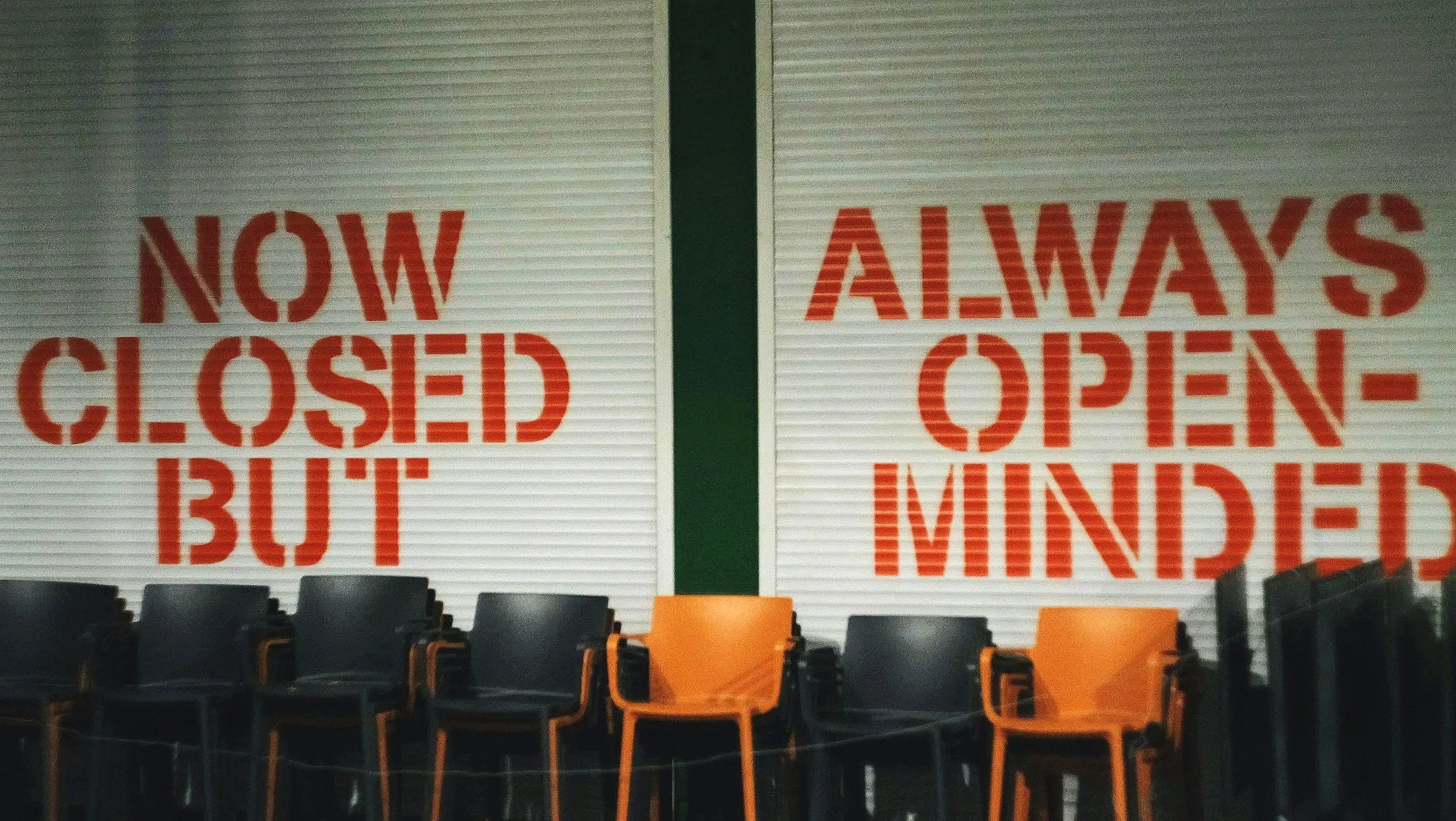 Image shows a sign on the wall that reads, "Now Closed But Always Open-Minded"