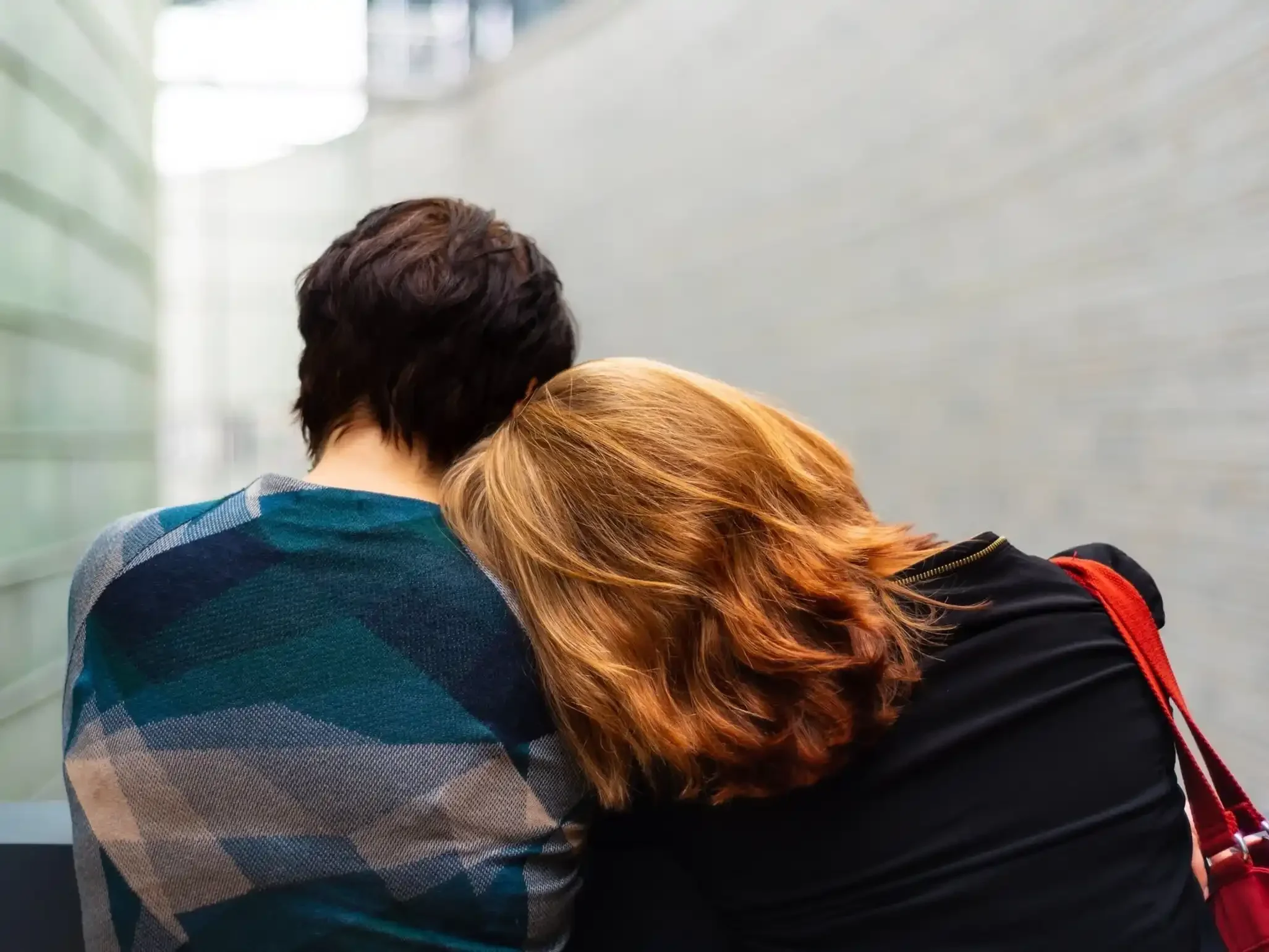 The back of a man and woman with the woman leaning her head on the man