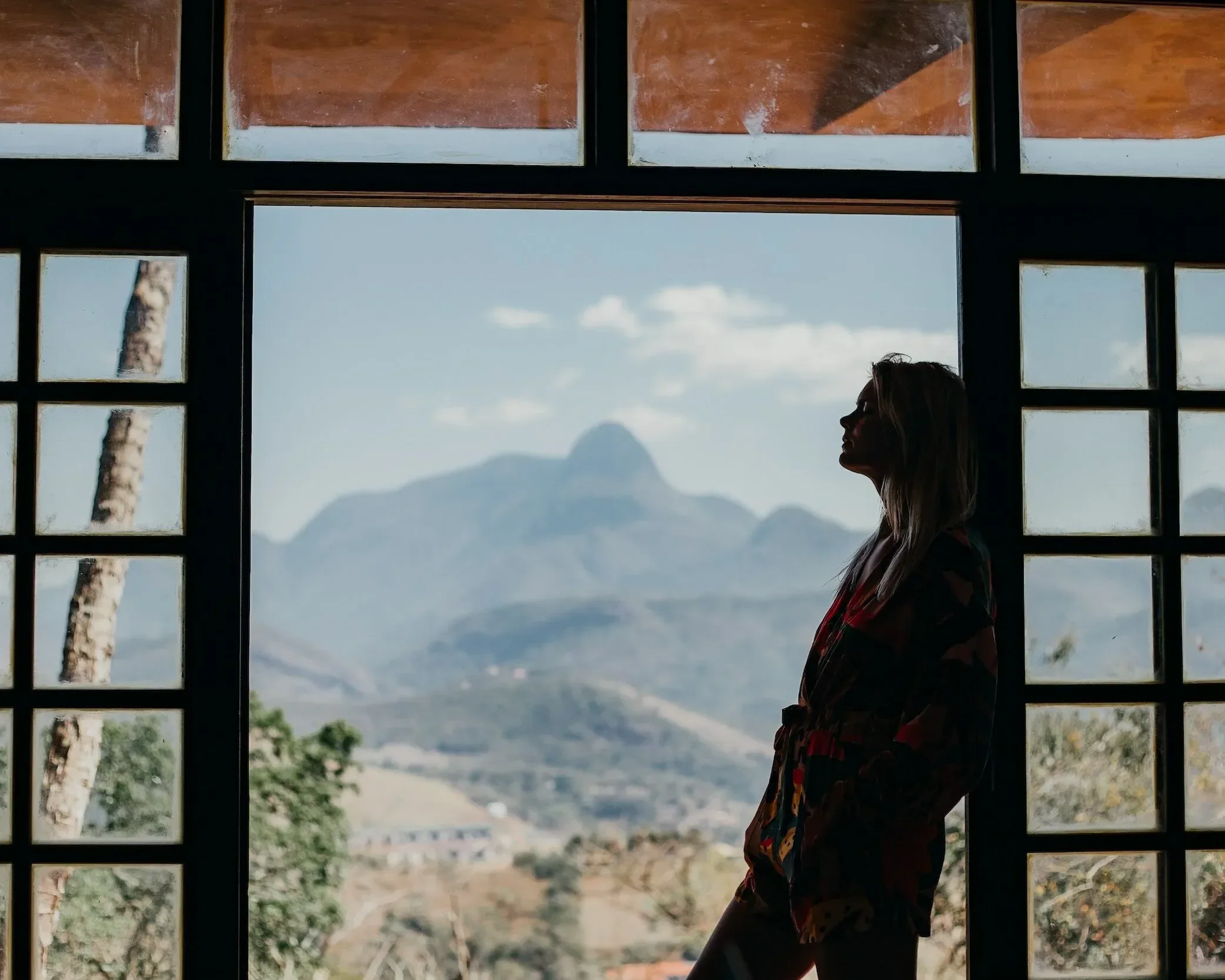 Woman leaning on open sliding door with mountains in background