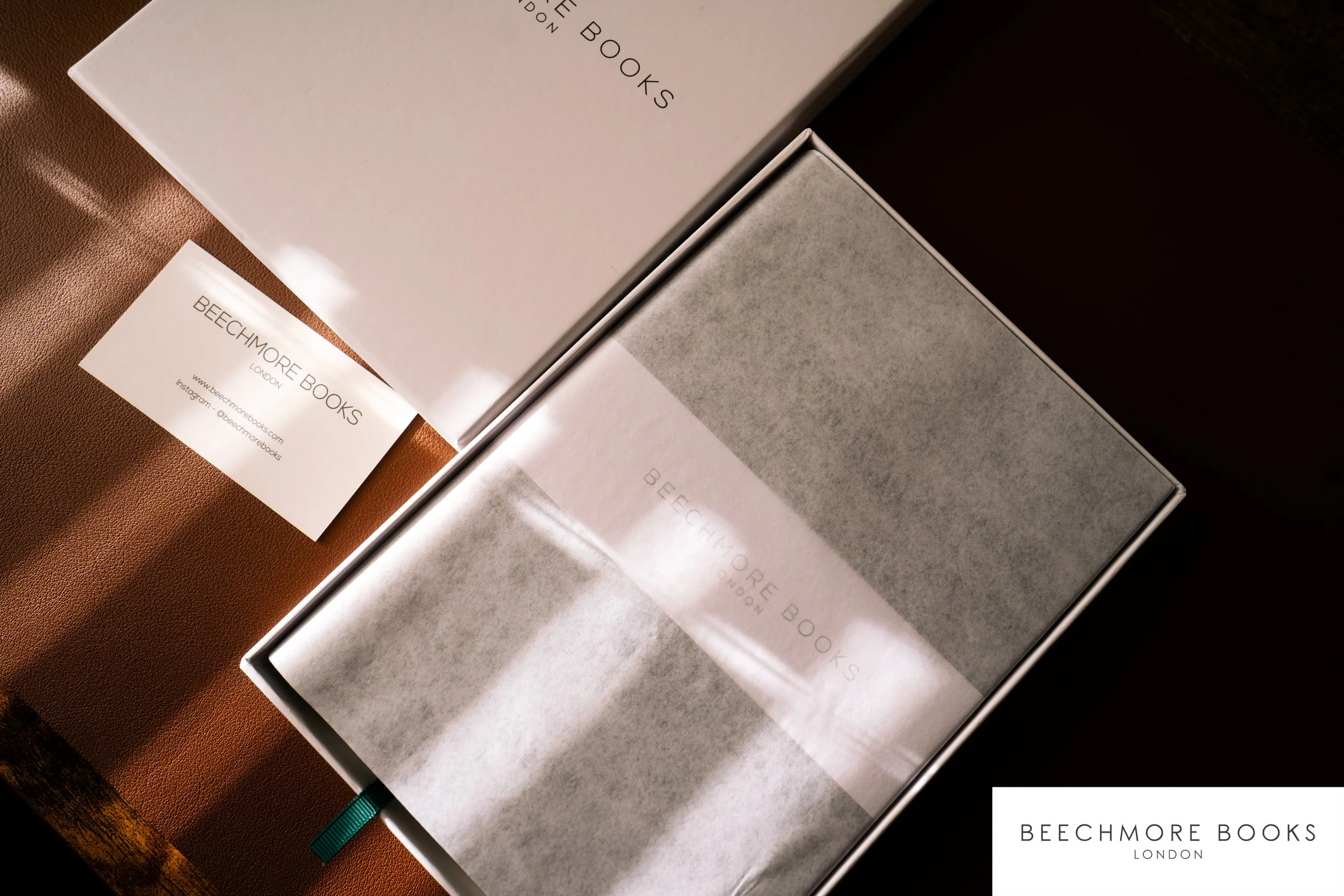 Multiple books from Beechmore Books, a London-based publisher, stacked on a surface with a library tag visible on one of them.