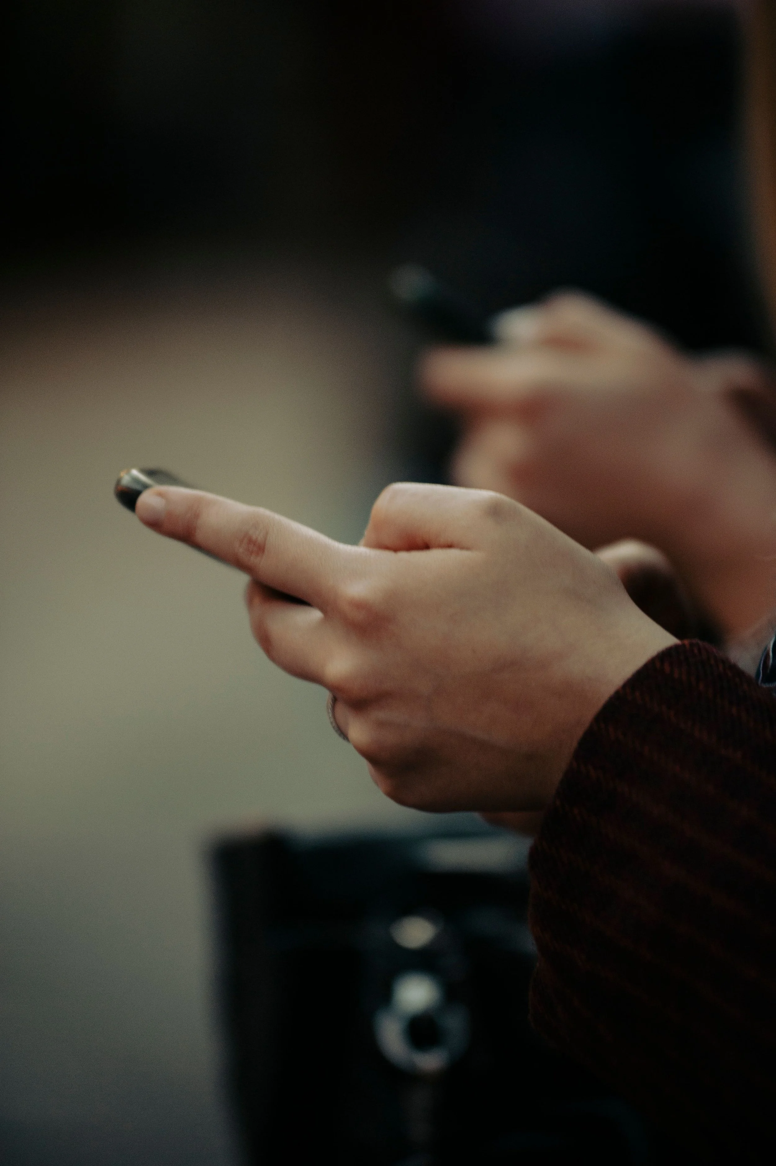 Close-up of a person holding a smartphone with both hands, with the face partially visible in the background.
