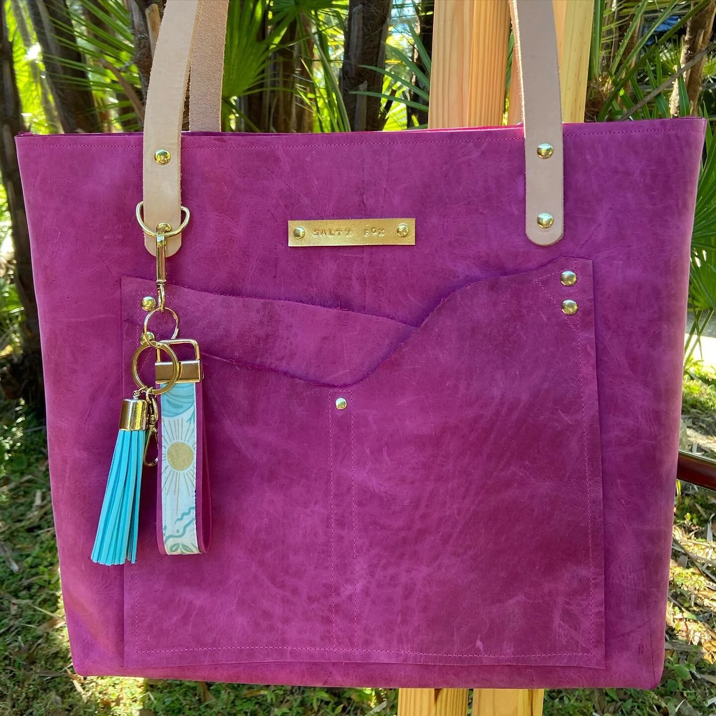 Fushia Florida vibes! 🌴 💕 This stunning leather bag is hitting the shop today with all my ready to ship inventory. 
.
.
.
She is a large size tote with 3 interior pockets, 3 exterior pockets and a magnetic snap to hold her shut. Tassel and handmade
