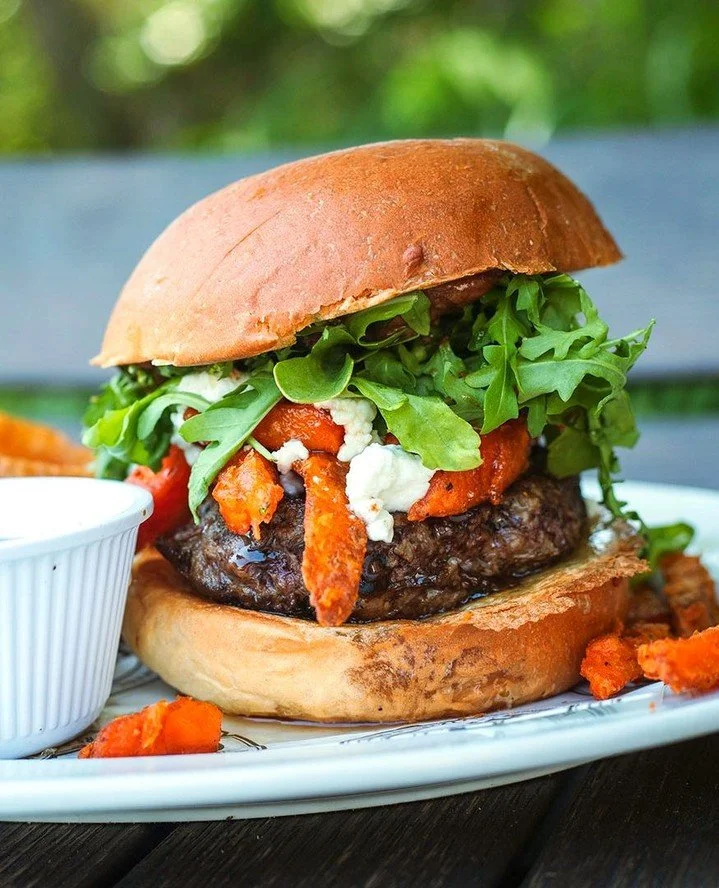 The burger equivalent of "trust us."⁠
⁠
The Cinna "Bomb" loads an all-natural Brandt burger with cinnamon aioli, brown sugar bacon, goat cheese, sweet potato fries and arugula on a buttery brioche roll. Then we hand you maple syru