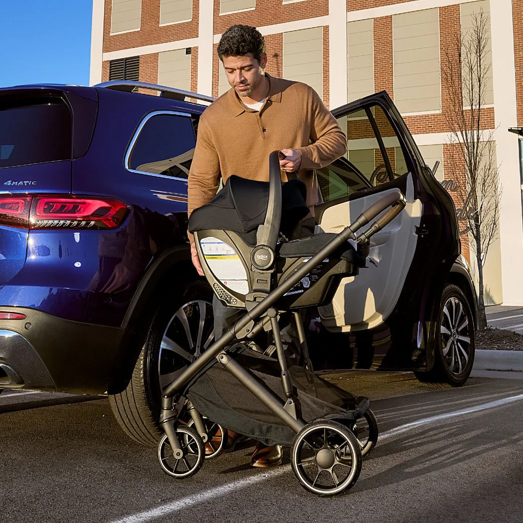 A man securing an infant car seat onto a stroller. 