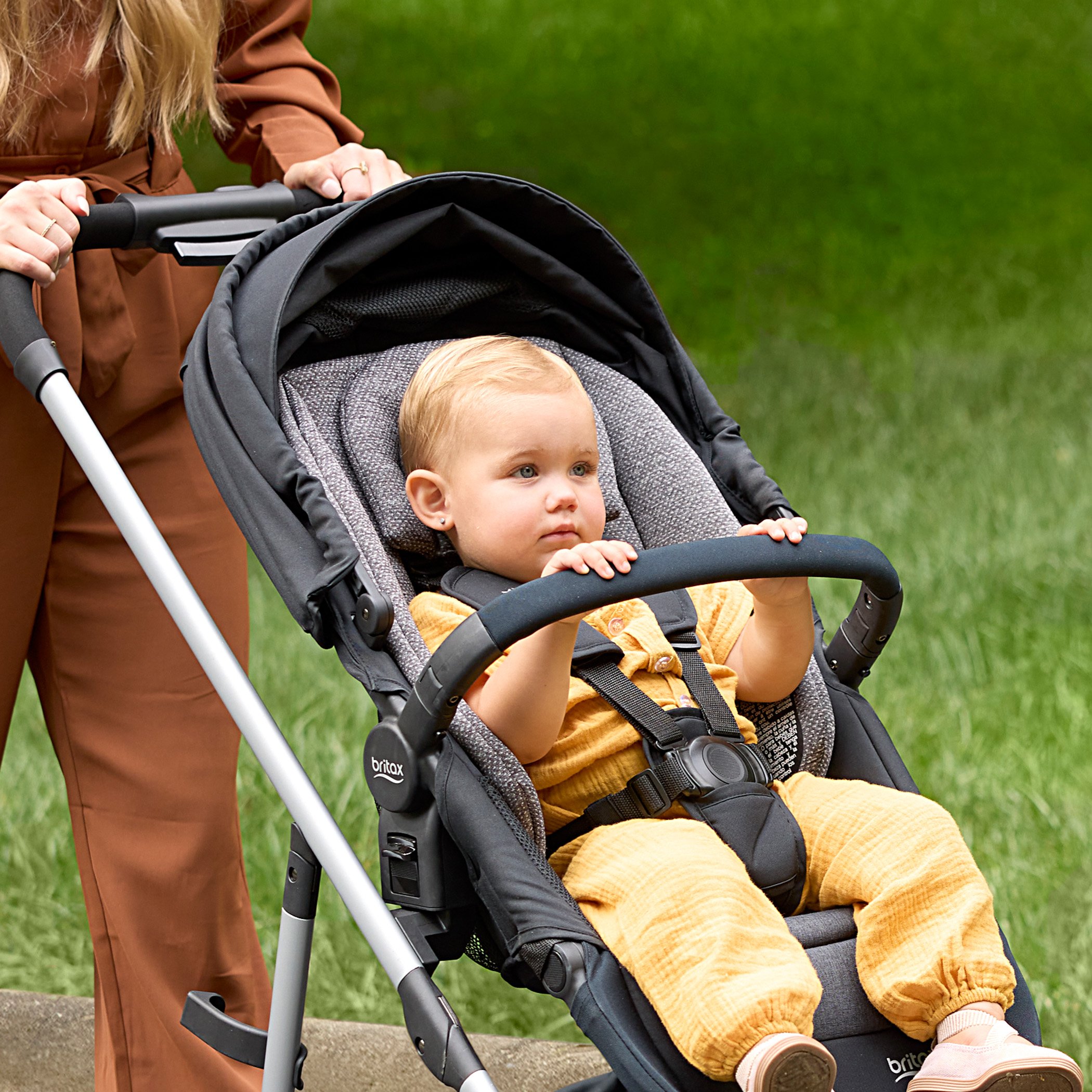 Lifestyle of child in a grove stroller holding onto the bumper bar (Copy)