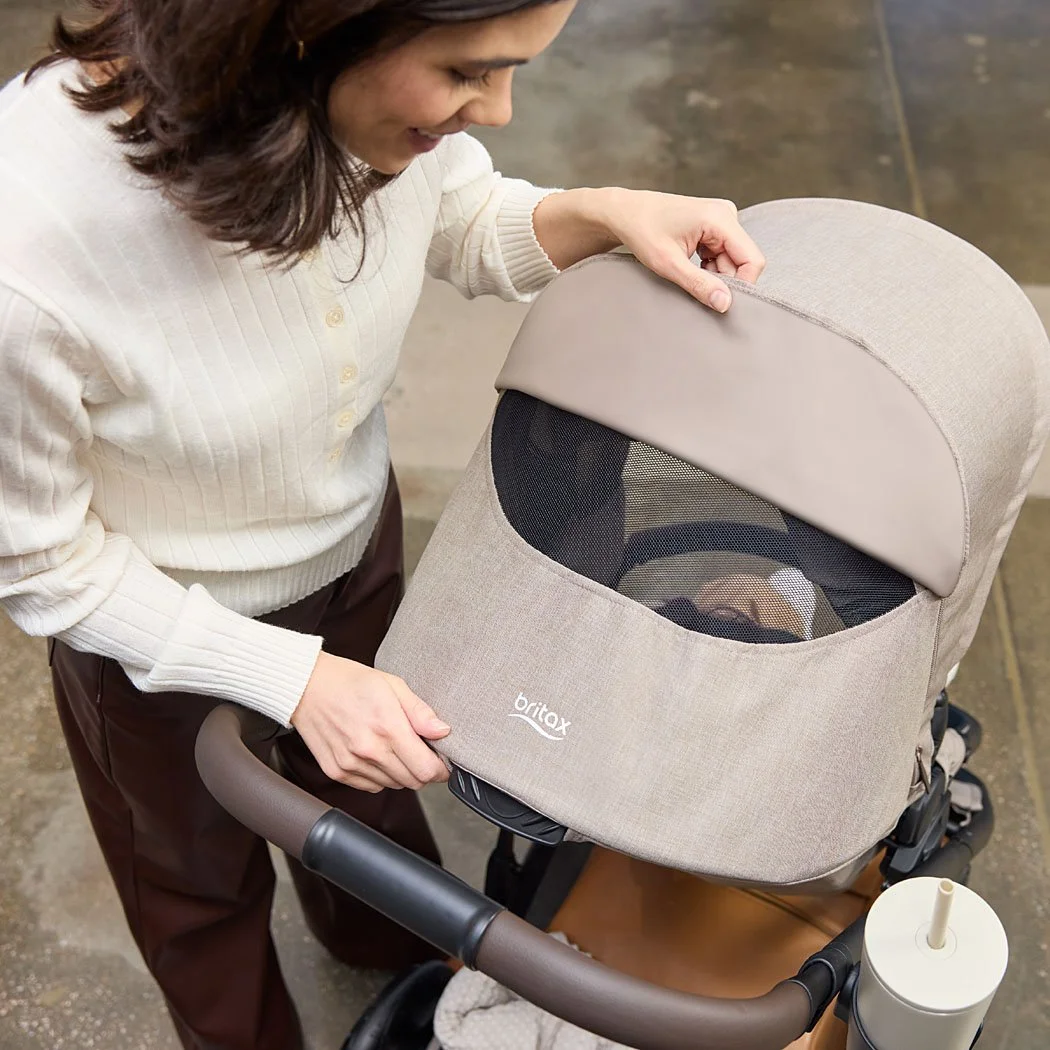 A woman looking through the mesh canopy window of a toddler/baby stroller.  