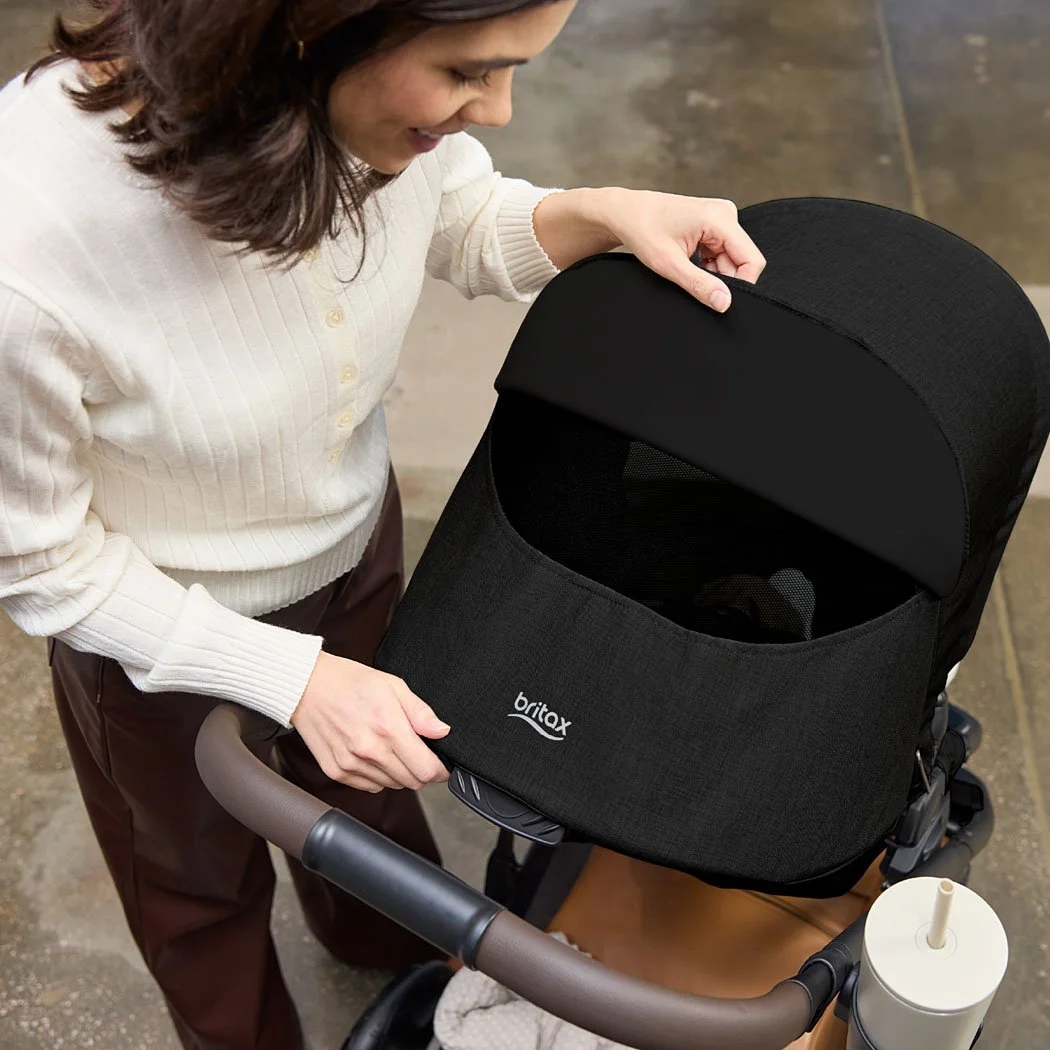 A woman looking through the mesh canopy window of a toddler/baby stroller.  