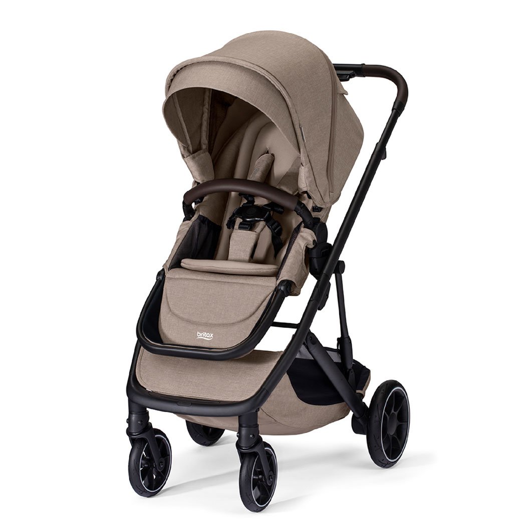 Poussette beige avec auvent, barre avant brune et logo Britax sur le repose-jambes. 