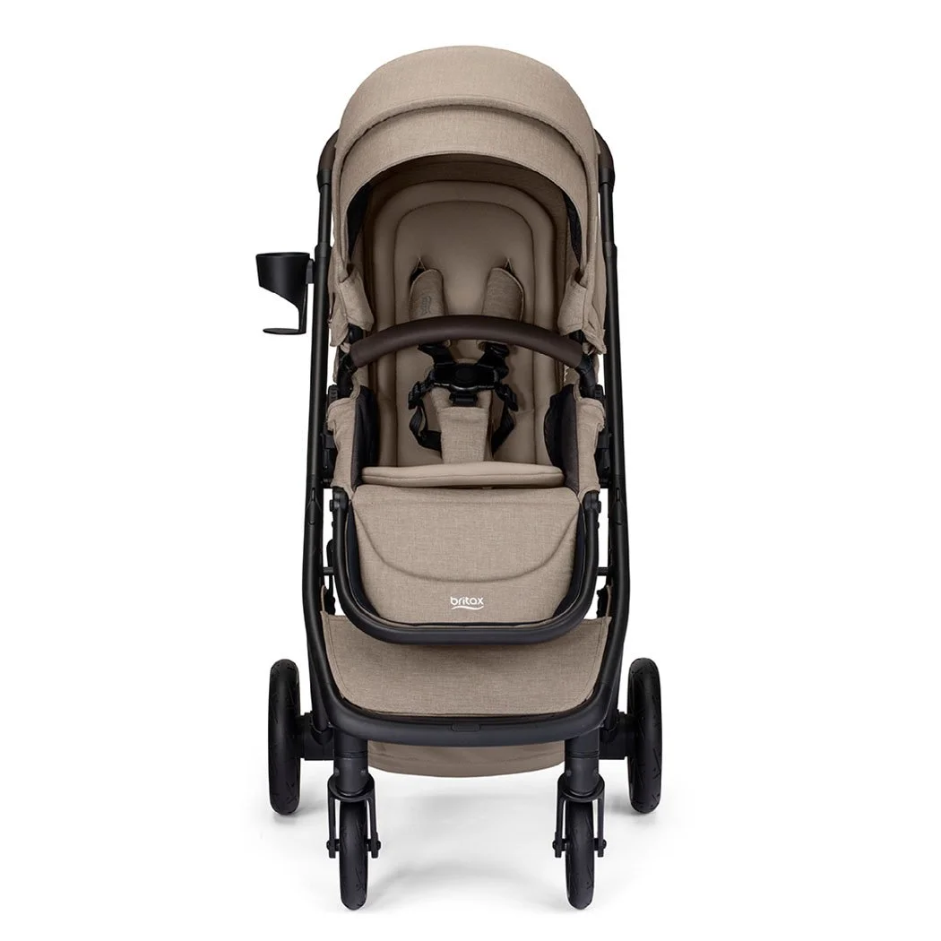 Poussette beige avec auvent, barre avant brune, porte-gobelet et logo Britax sur le repose-jambes. 