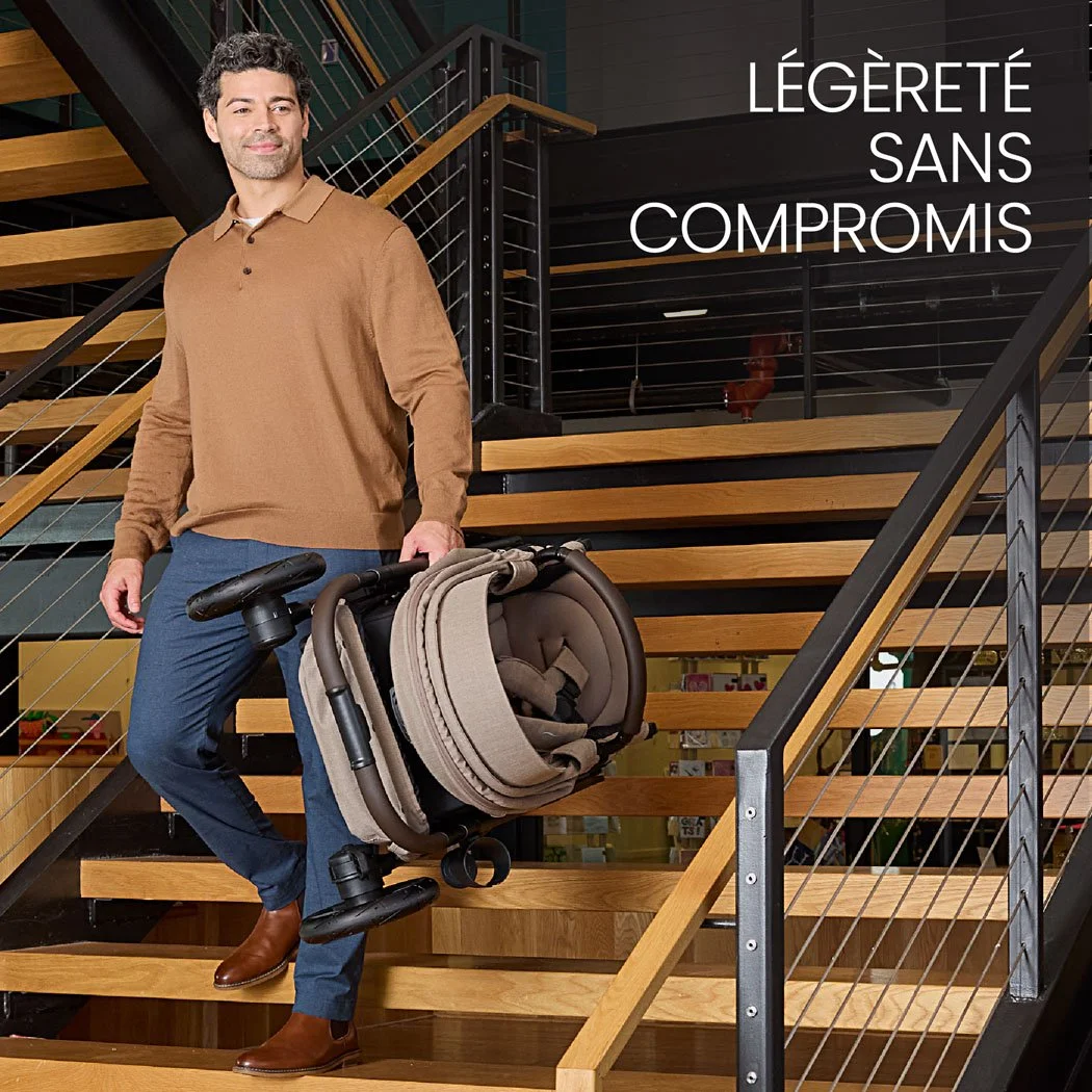 Légère sans compromis. Un homme transporte une poussette pliée dans un escalier intérieur. 
