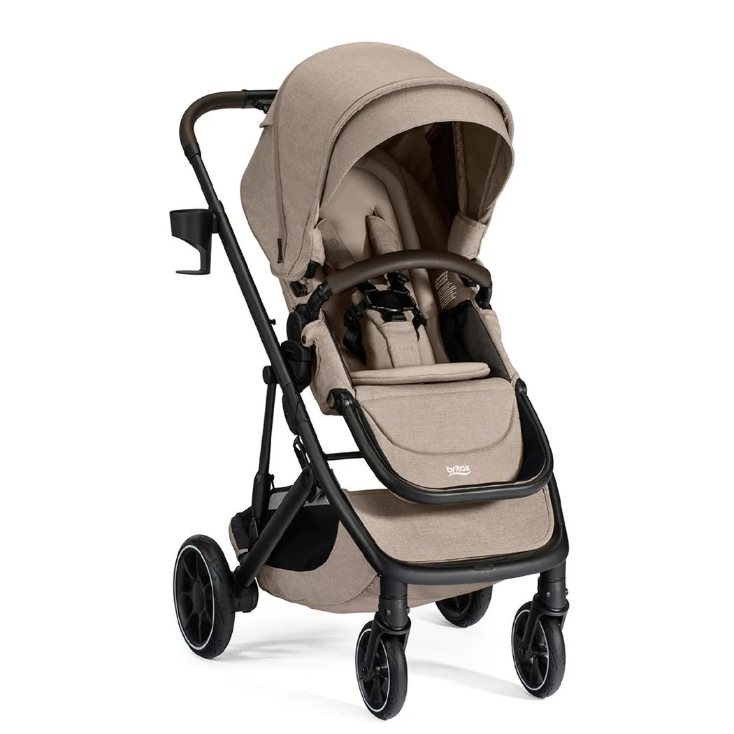 A tan stroller with a canopy, a brown bumper bar, a cup holder, and the Britax logo on the leg rest.