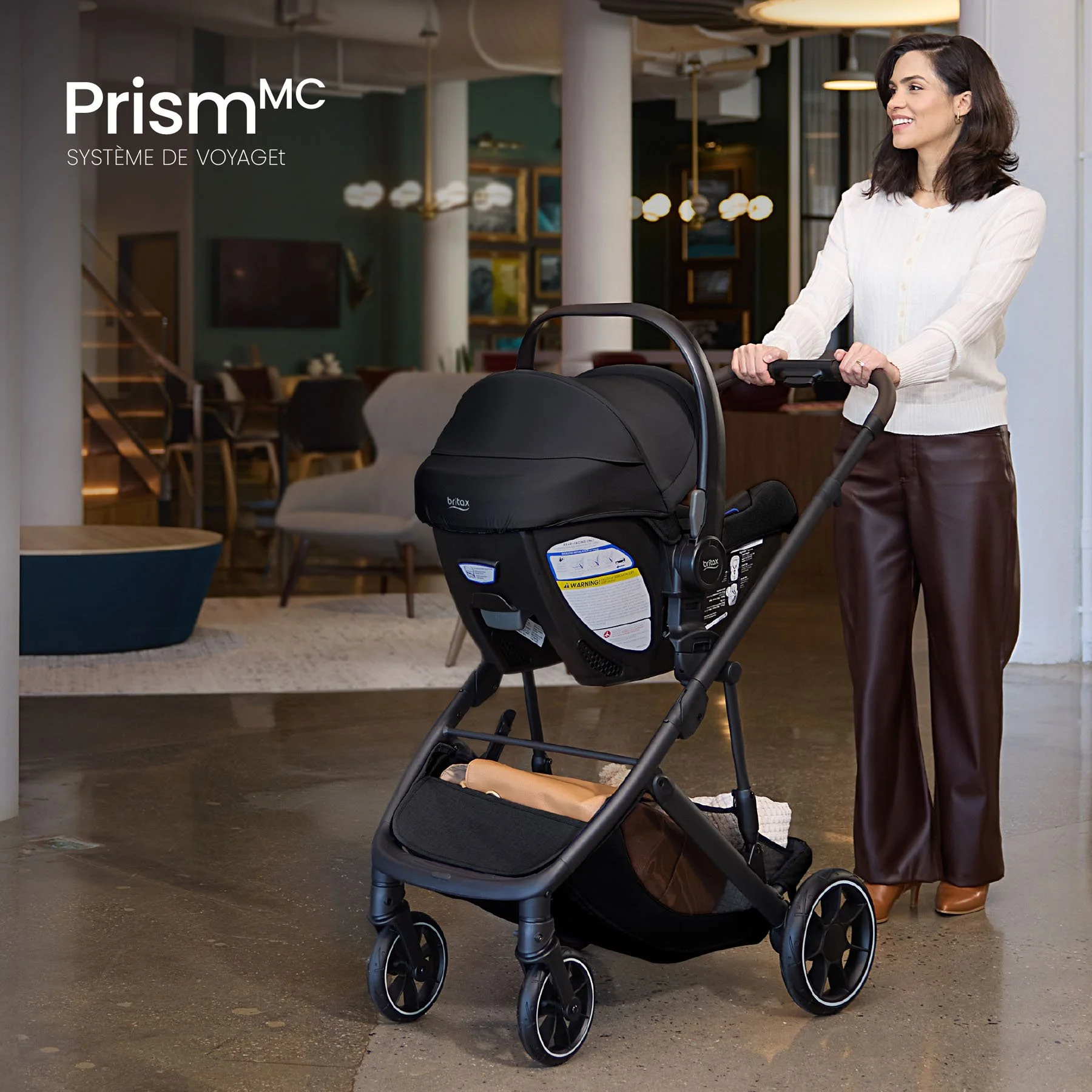 Système de voyage Prism. Une femme poussant une poussette équipée d’un siège d’auto pour nourrisson.  