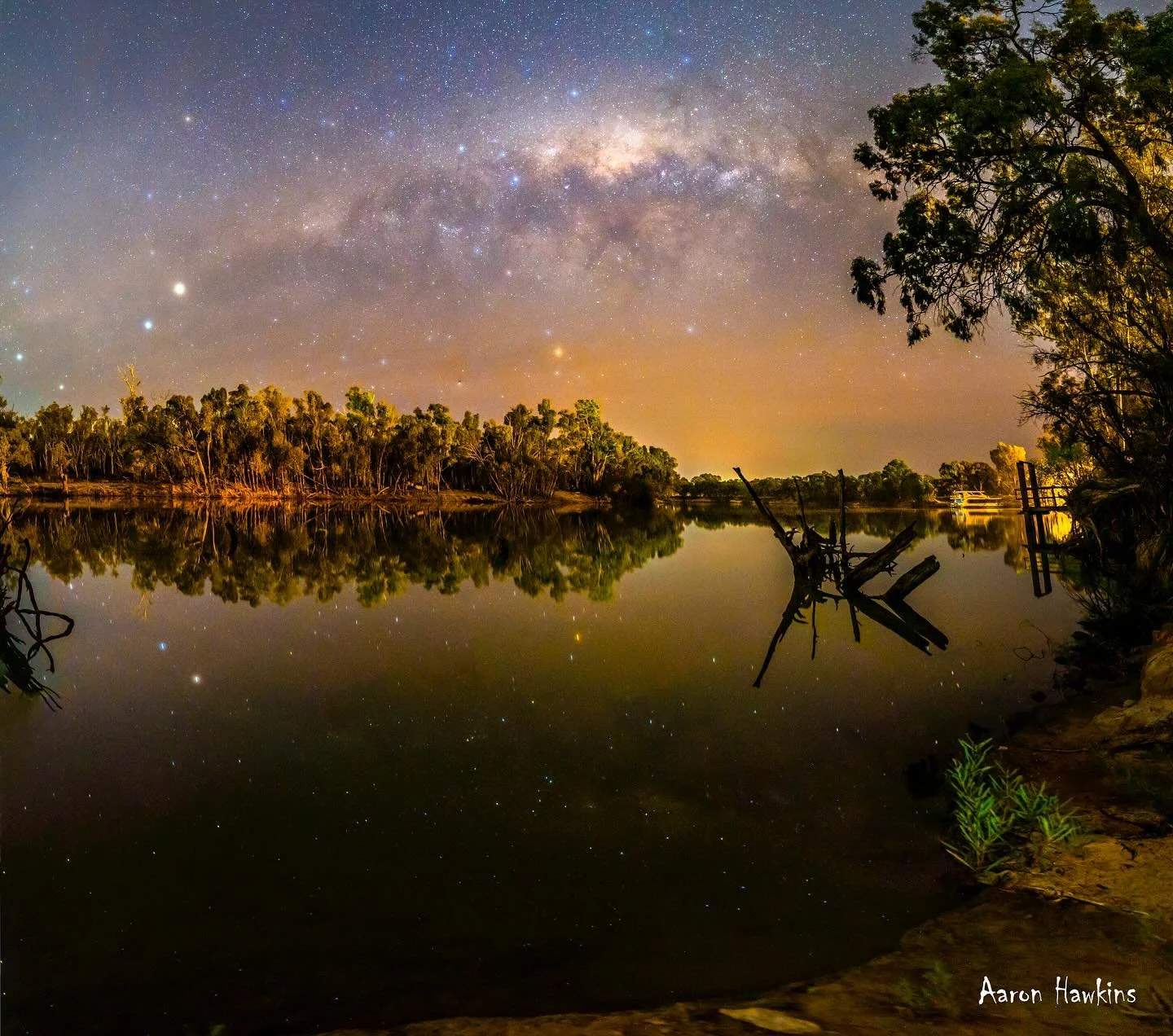 Home sweet home ❤️

The Milky Way sets over our home river bend. Pump station, wharf, iconic houseboat and golf club in the background while the lights of Dareton shine on the river gums reflected with the stars in the seemingly still water. A scene 