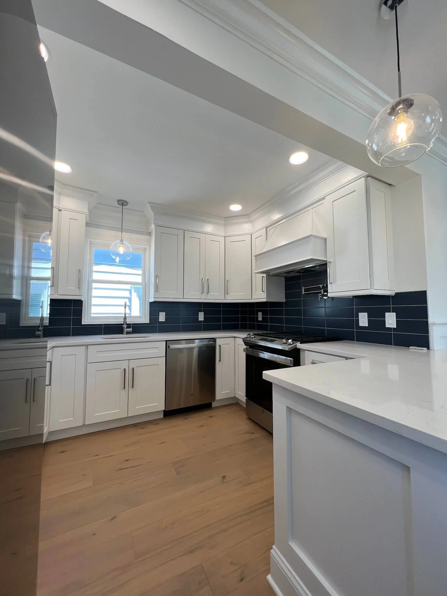 Ocean City two-tone coastal kitchen featuring white uppers, blue base cabinets, an oversized island, rattan seating, and quartz countertops by 2B Contracting.