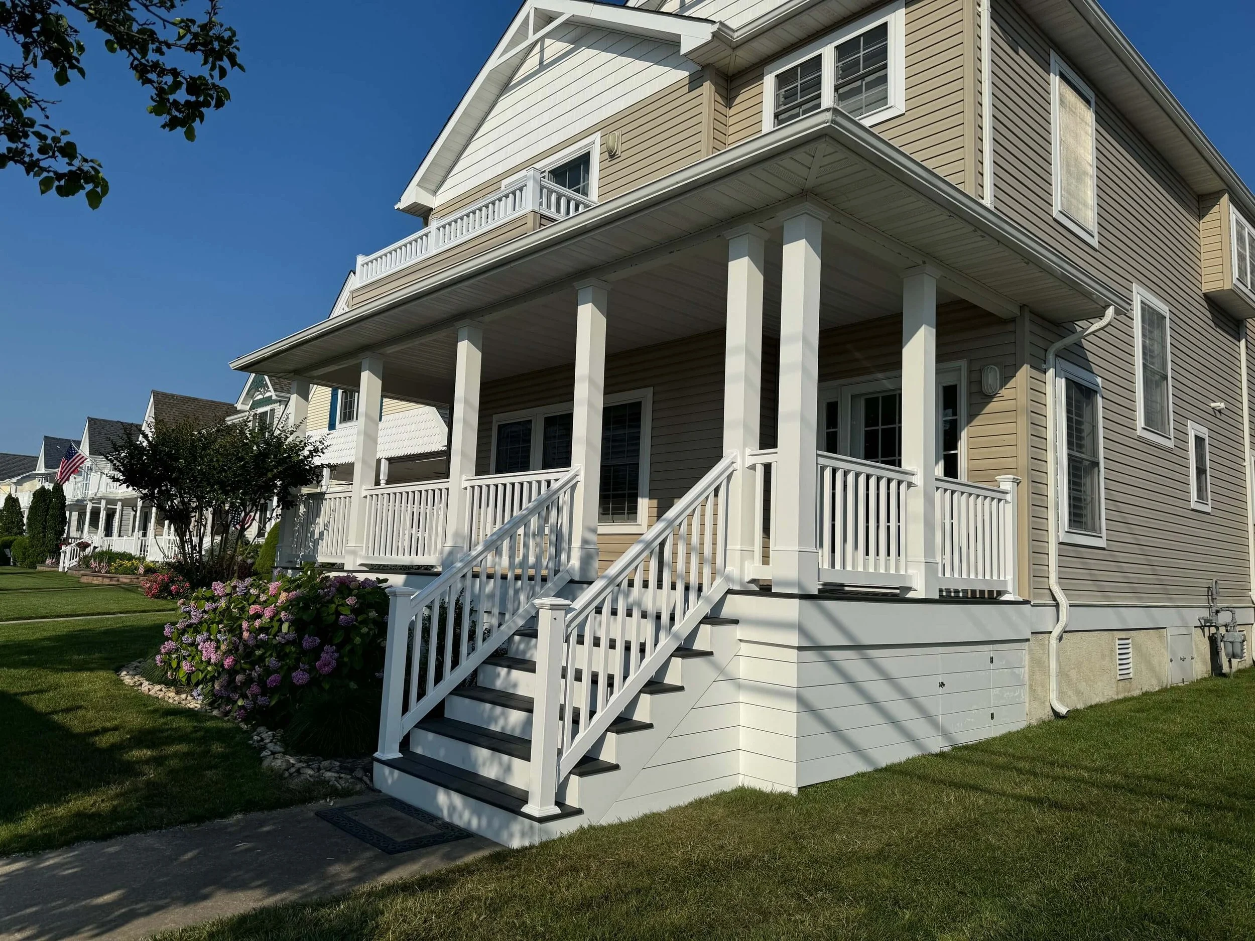 Custom coastal porch renovation featuring white columns, modern railings, and lattice trim in Ocean City, NJ.