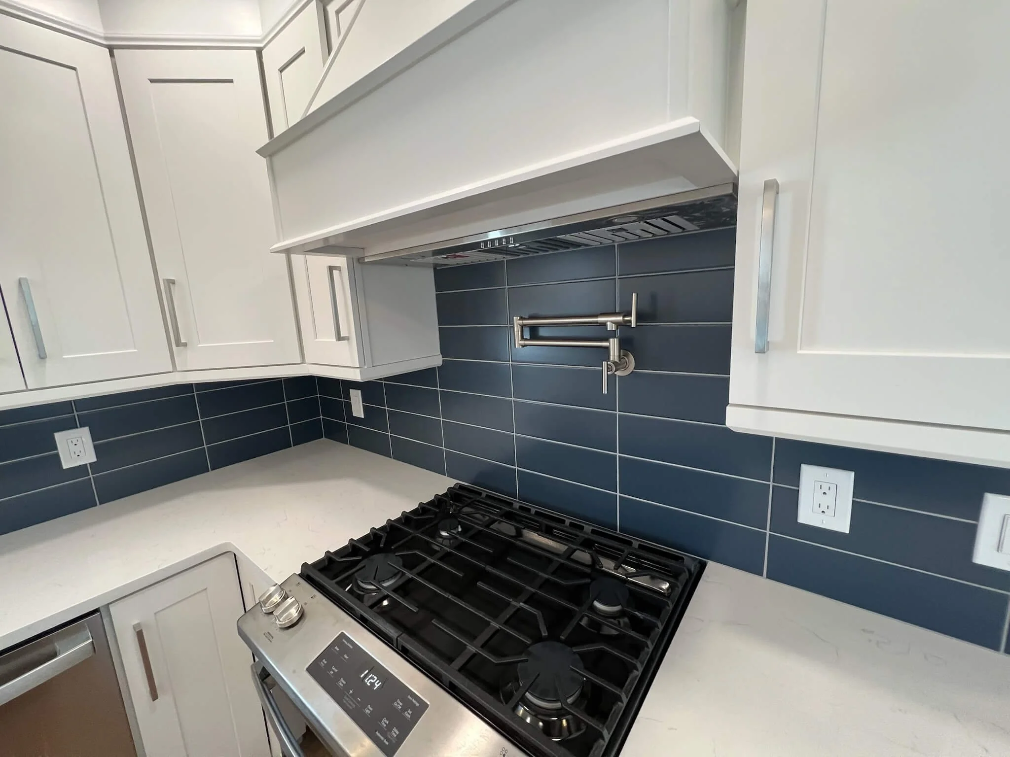 White shaker kitchen with navy subway tile backsplash and pot filler installed by 2B Contracting in Ocean City, NJ.