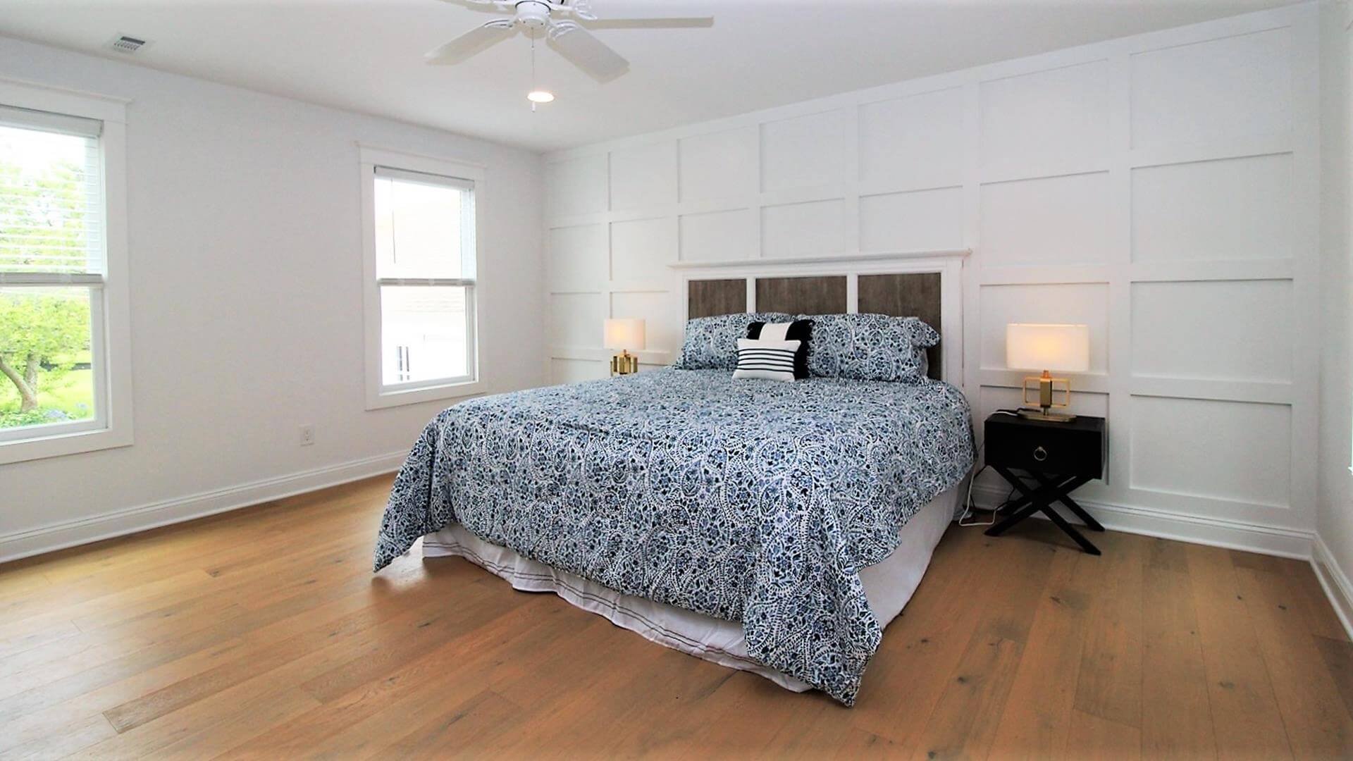Ocean City primary bedroom with custom trim accent wall and natural oak flooring by 2B Contracting.