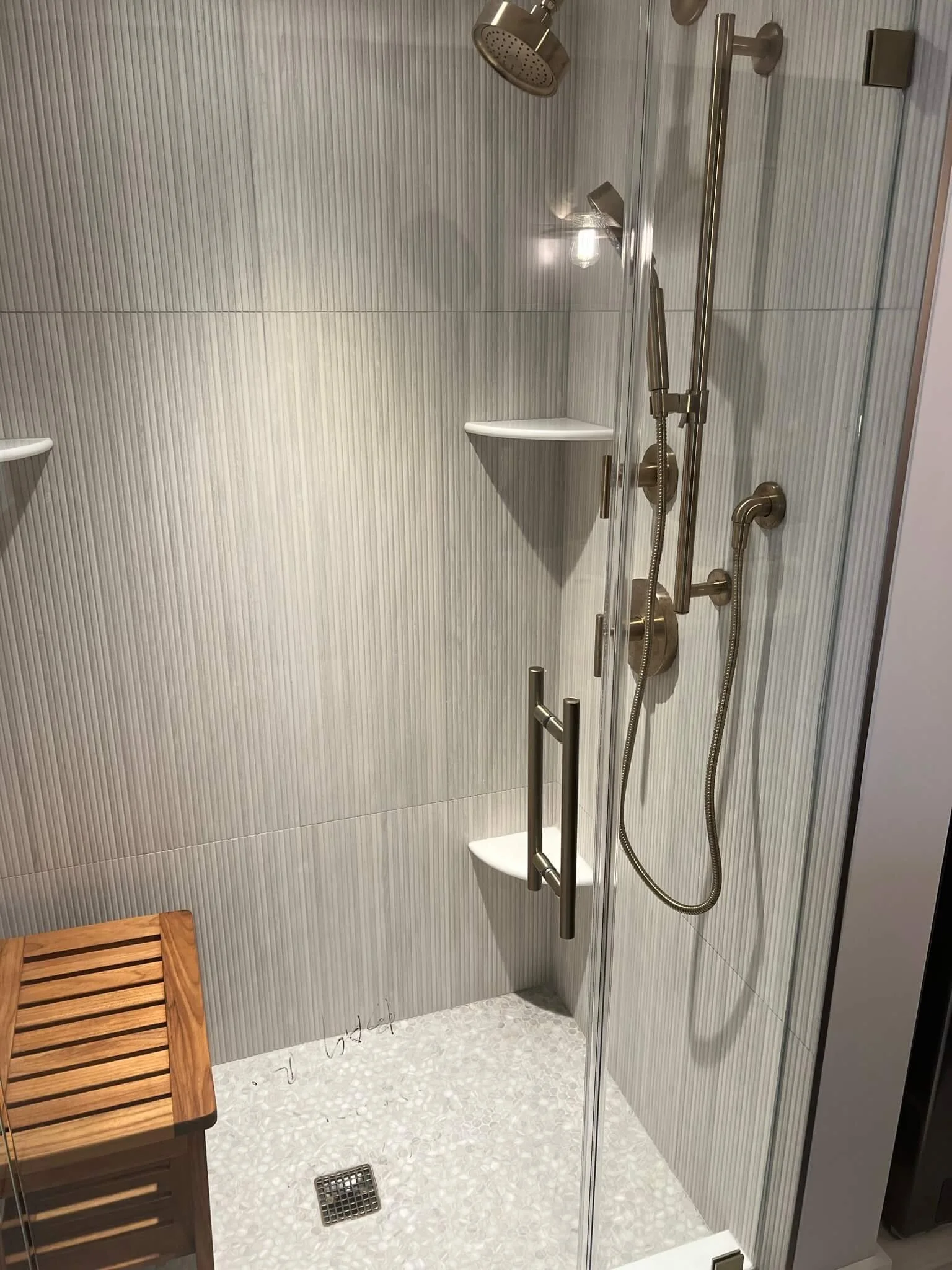 Vertical blue ceramic shower tile with quartz bench and rainfall showerhead in a luxury Ocean City bathroom