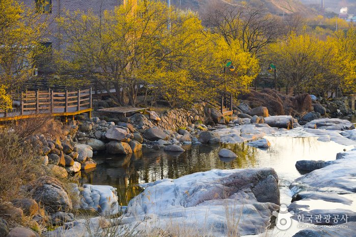 Photo of a creek with big rocks and a wooden walkway in Gurye Sansuyu