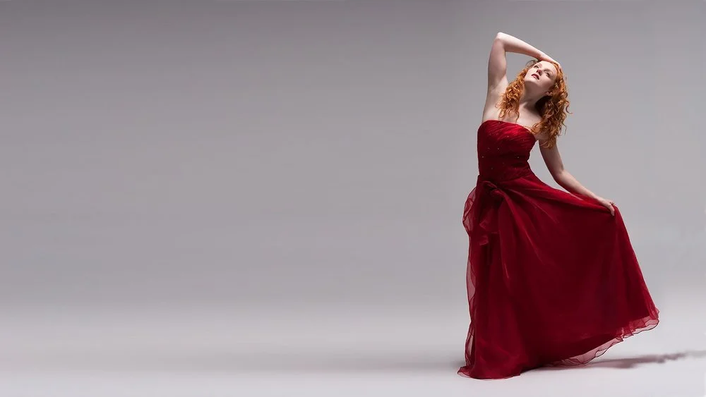 a model poses in a red ball gown for a website