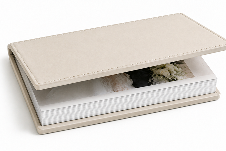Closed ivory Marquis Album with photographic pages visible between stitched covers