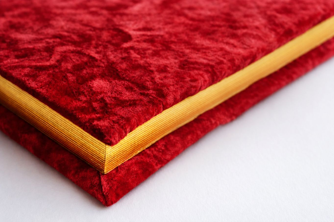 Red velvet handcrafted photo album with gold-edged pages.png