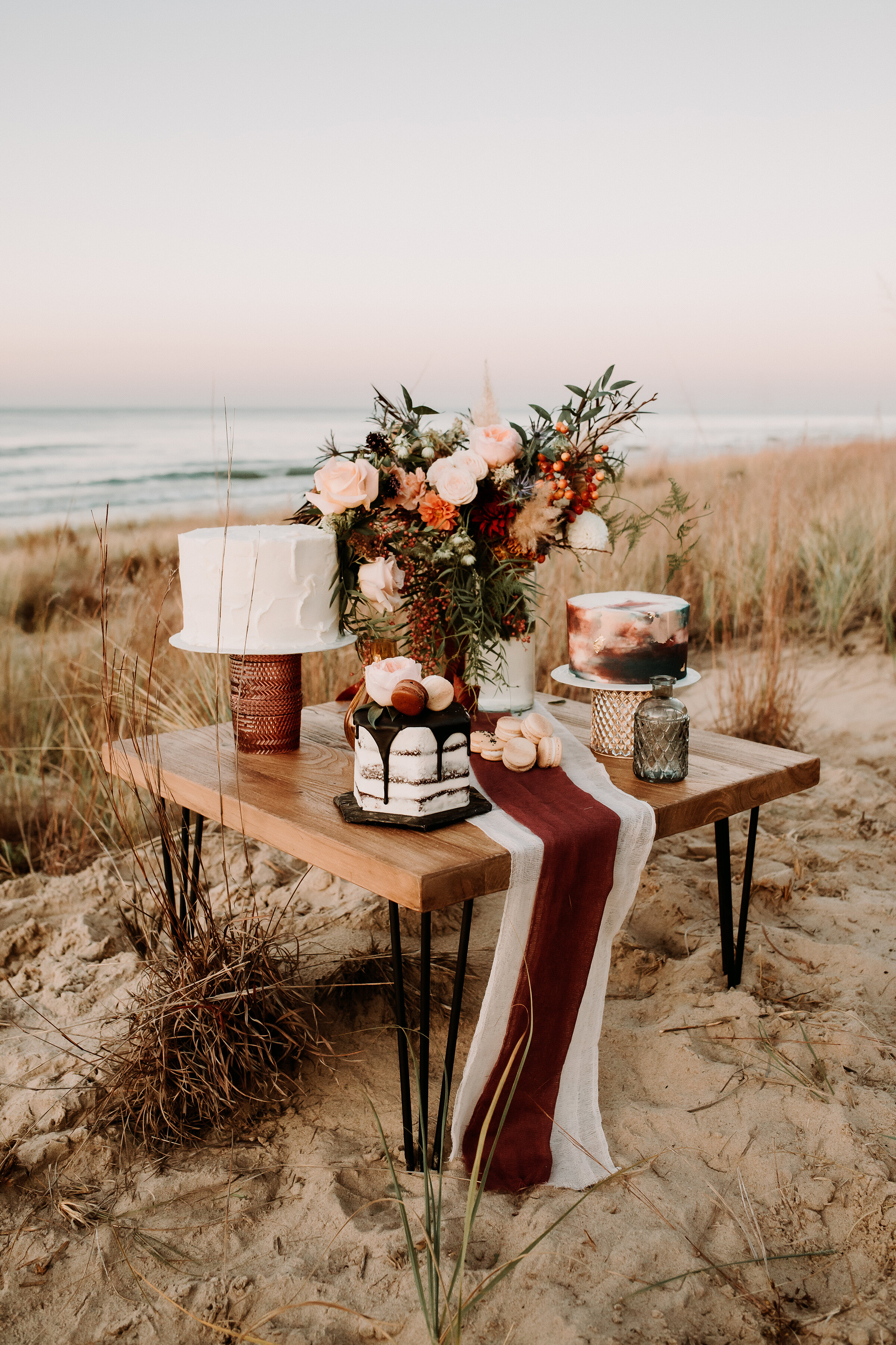  A trio of cakes and boho table decor for this west coast-inspired elopement styled shoot on the shores of Lake Michigan in Indiana Dunes State Park. adventurous brides planning boho weddings in the midwest cake display table boho wedding beach elope