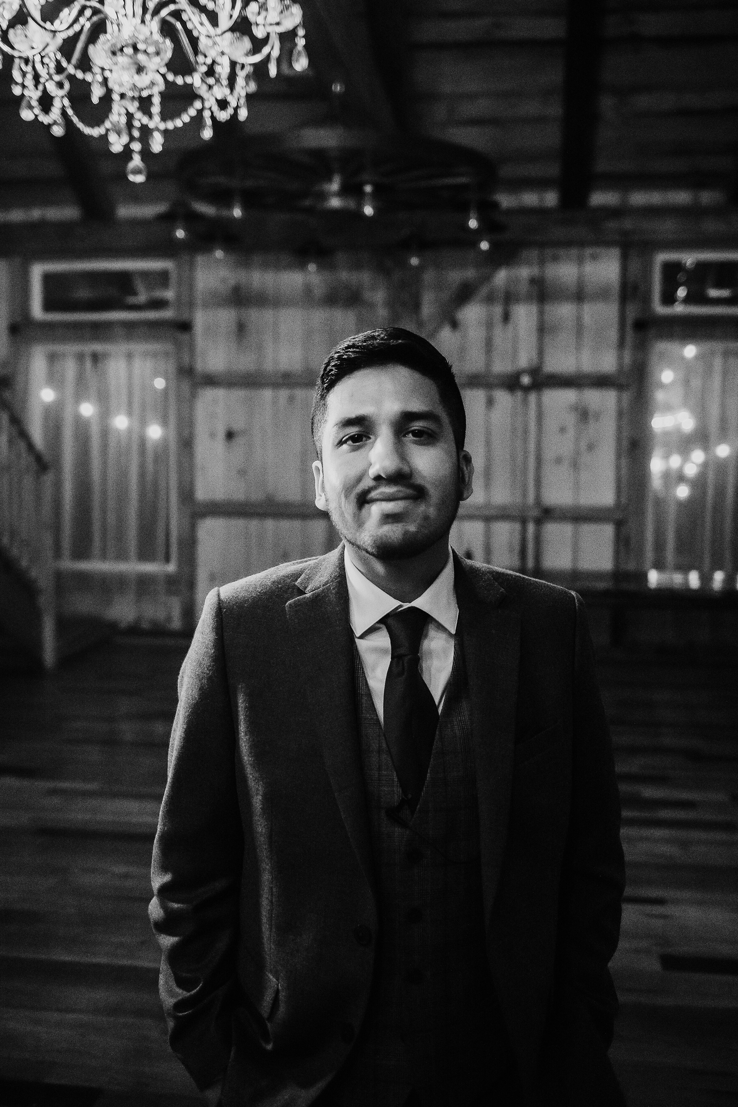  Kindred + Co. Photography captures this eager groom moments before tying the knot at this treehouse elopement at the Grand Barn at the Mohicans in Akron, Ohio. black and white photo, crystal chandelier, treehouse wedding, string lights, groom, tween