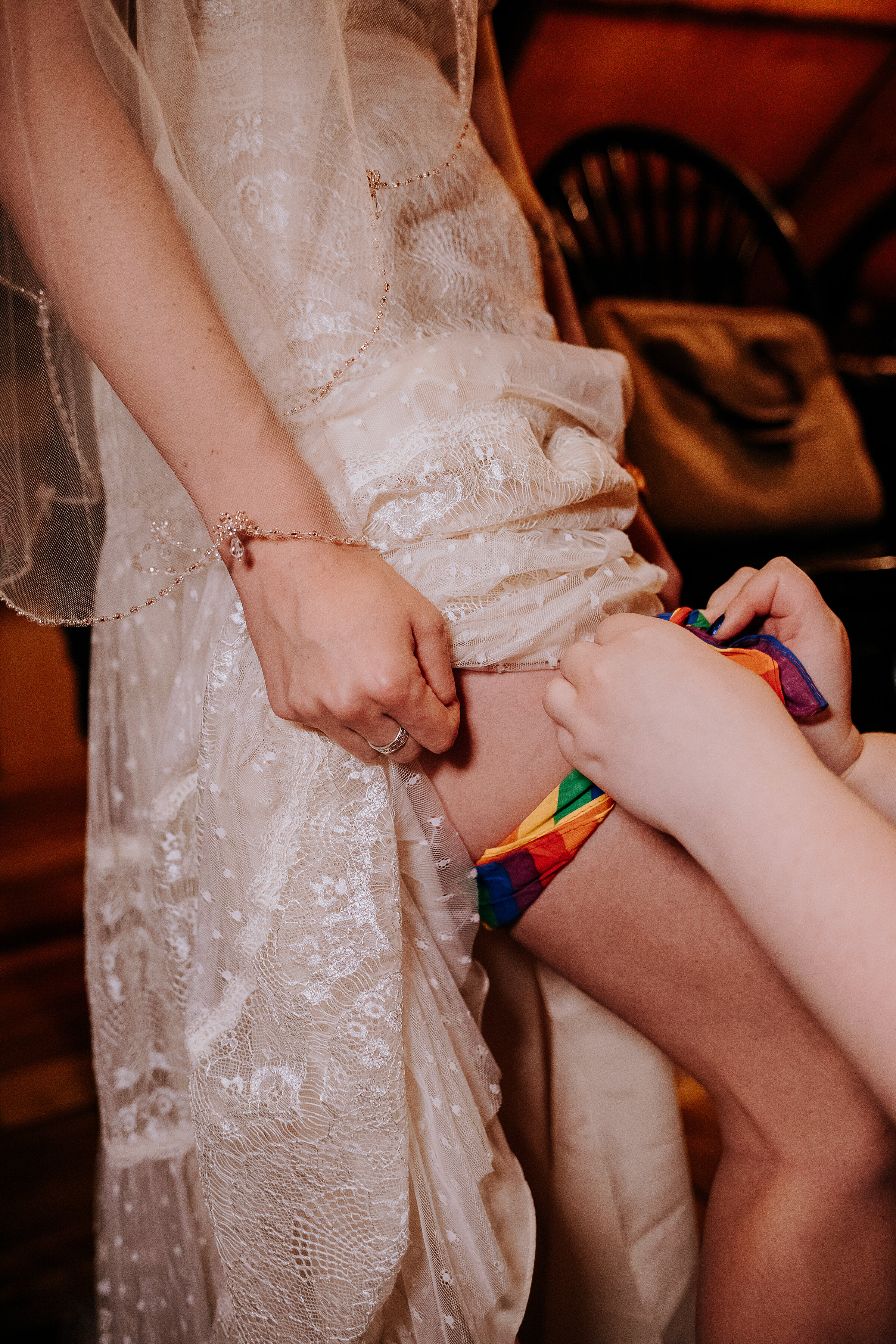  Kindred + Co. Photography captures authentic celebratory moments as groom removes his bride’s garter in this unique treehouse wedding elopement at the Mohicans. rainbow garter, lace bohemian wedding dress, beaded waist length bridal veil, candid cel