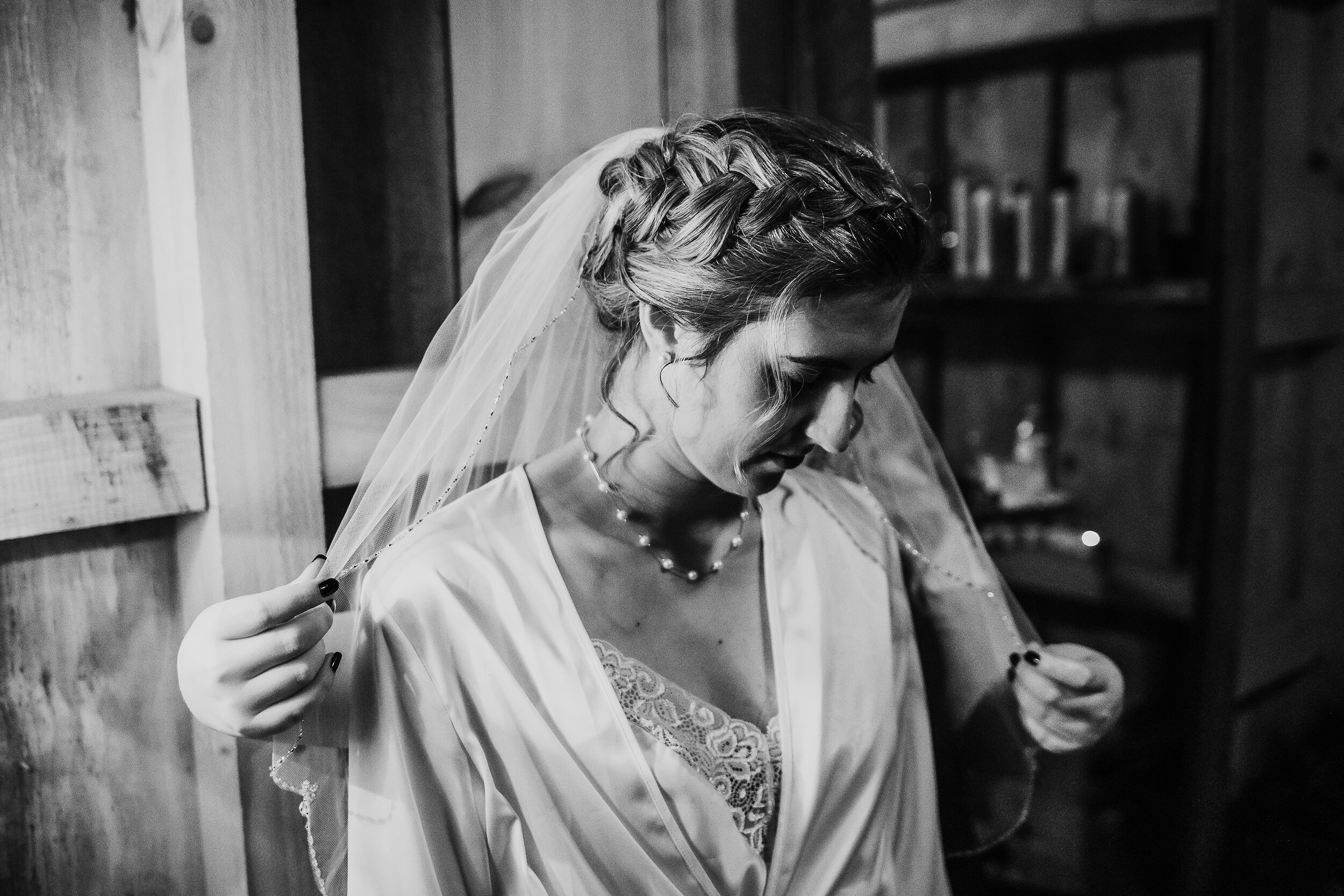  Kindred + Co. Photography captures the final details of bride’s wedding look on the morning of her elopement in Akron, Ohio. bohemian bride, pearl minimalist necklace, bohemian braided wedding updo, white satin wedding robe, wedding morning, natural