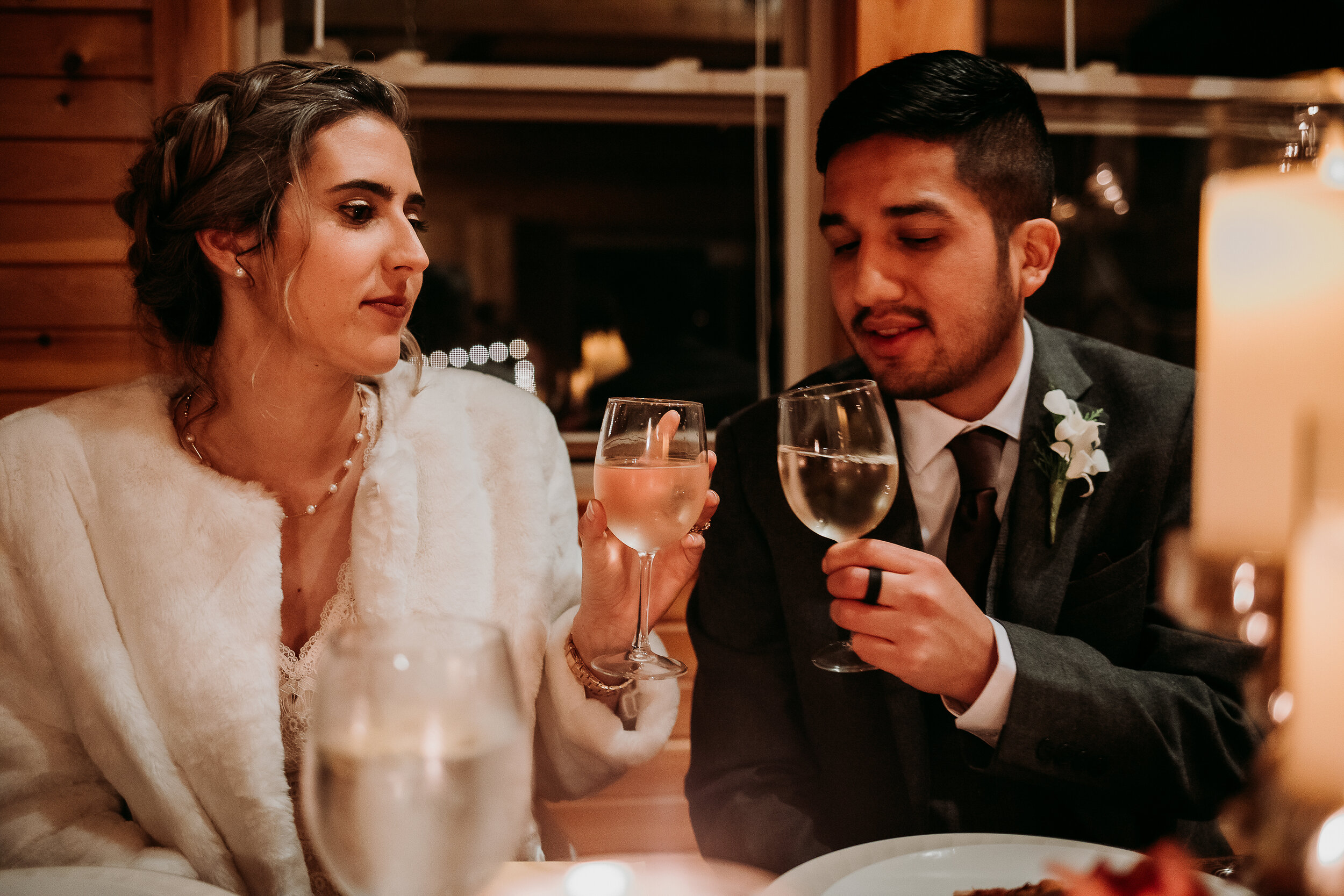  Kindred + Co. Photography captures romantic dinner moments following an evening treehouse elopement at the Grand Barn at the Mohicans. candlelit wedding dinner, elopement dinner, wedding fur shawl, bohemian wedding braided updo, pearl wedding neckla