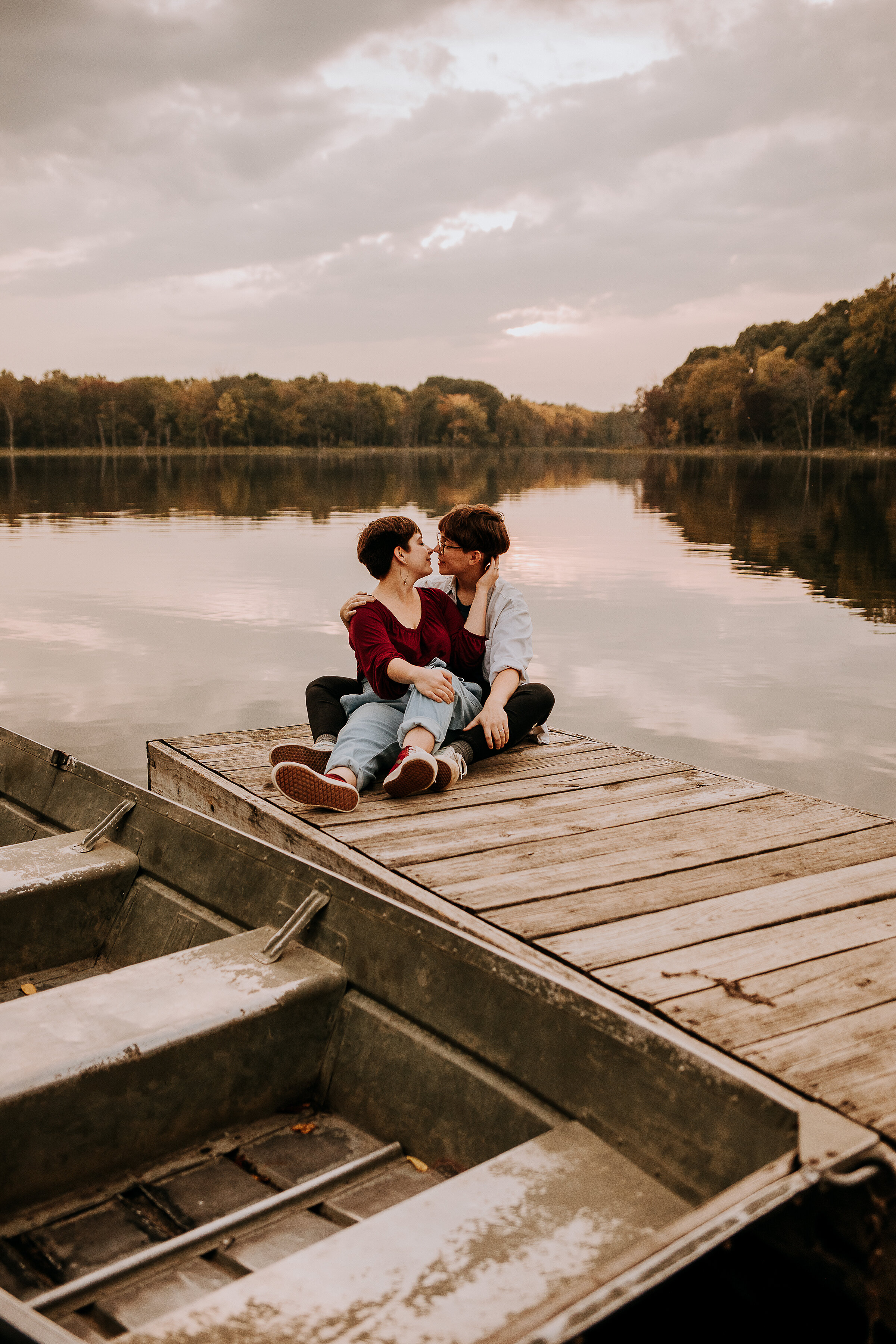  Gorgeous same-sex couple posing on dock with boat by lake in this fall photoshoot by Kindred + Co in Indiana. lake locations in indiana for photoshoot outdoor photoshoot in fort wayne indiana same-sex wedding photography engagement photos pose inspo