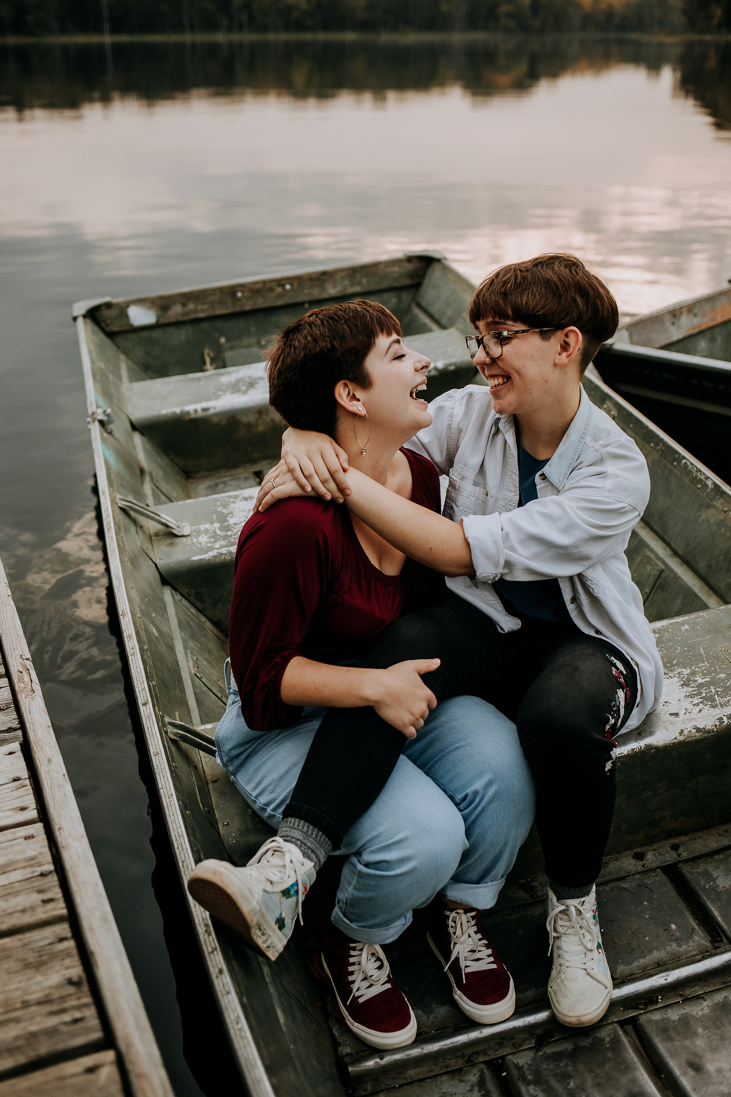  Cute candid shot of same-sex couple in a boat on a lake laughing wearing maroon and gray in Indiana by Kindred + Co. photoshoot with boat on a dock by a lake fort wayne indiana outdoor photoshoot locations by a lake fall photo outfit inspo with maro