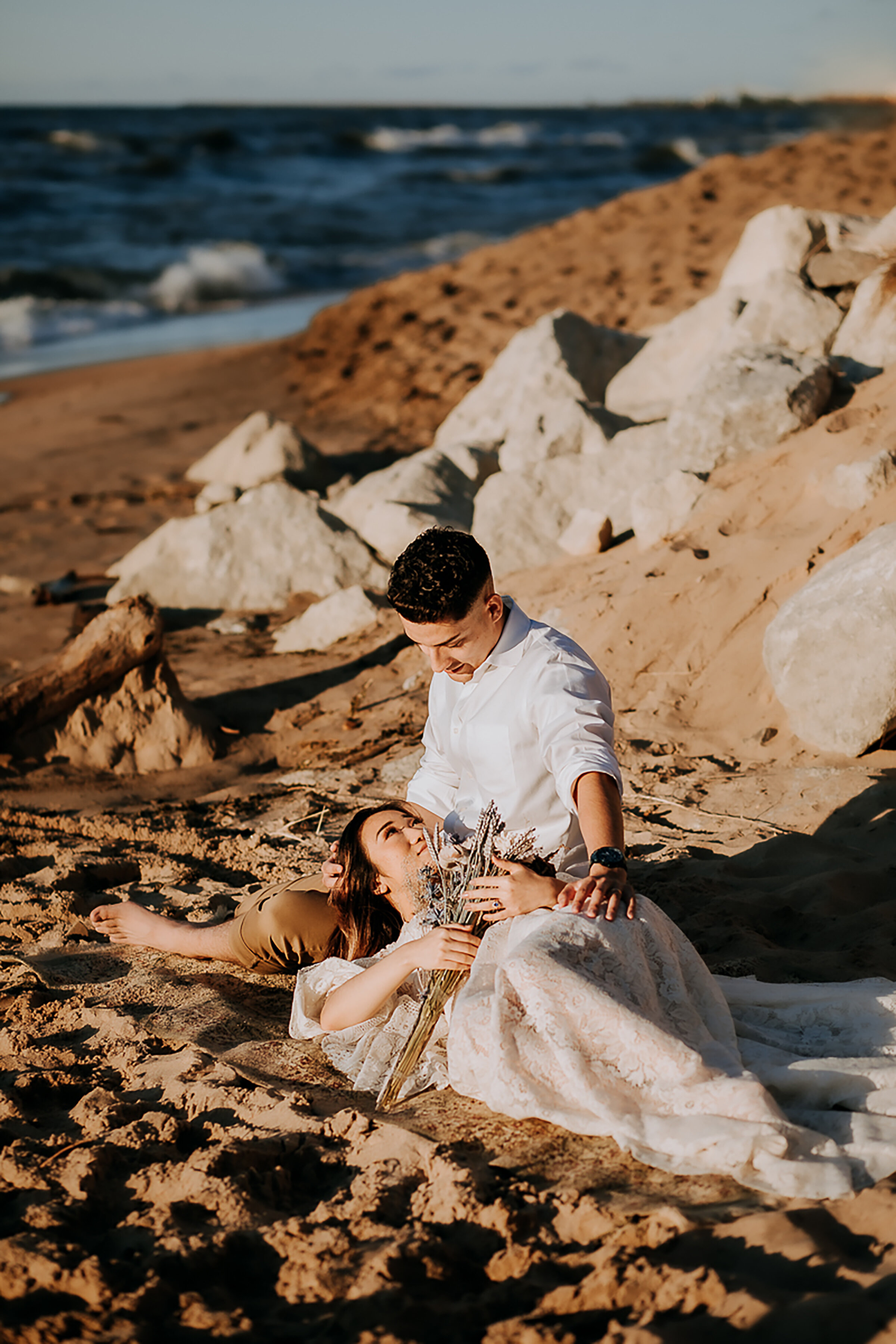 Kindred &amp; Co. Photography captures newly eloped couple romantically lounging on the sandy beach of Indiana Dunes State Park. loose lace bohemian elopement dress, long loose full length beach dress, dried floral and grass wedding bouquet, profess