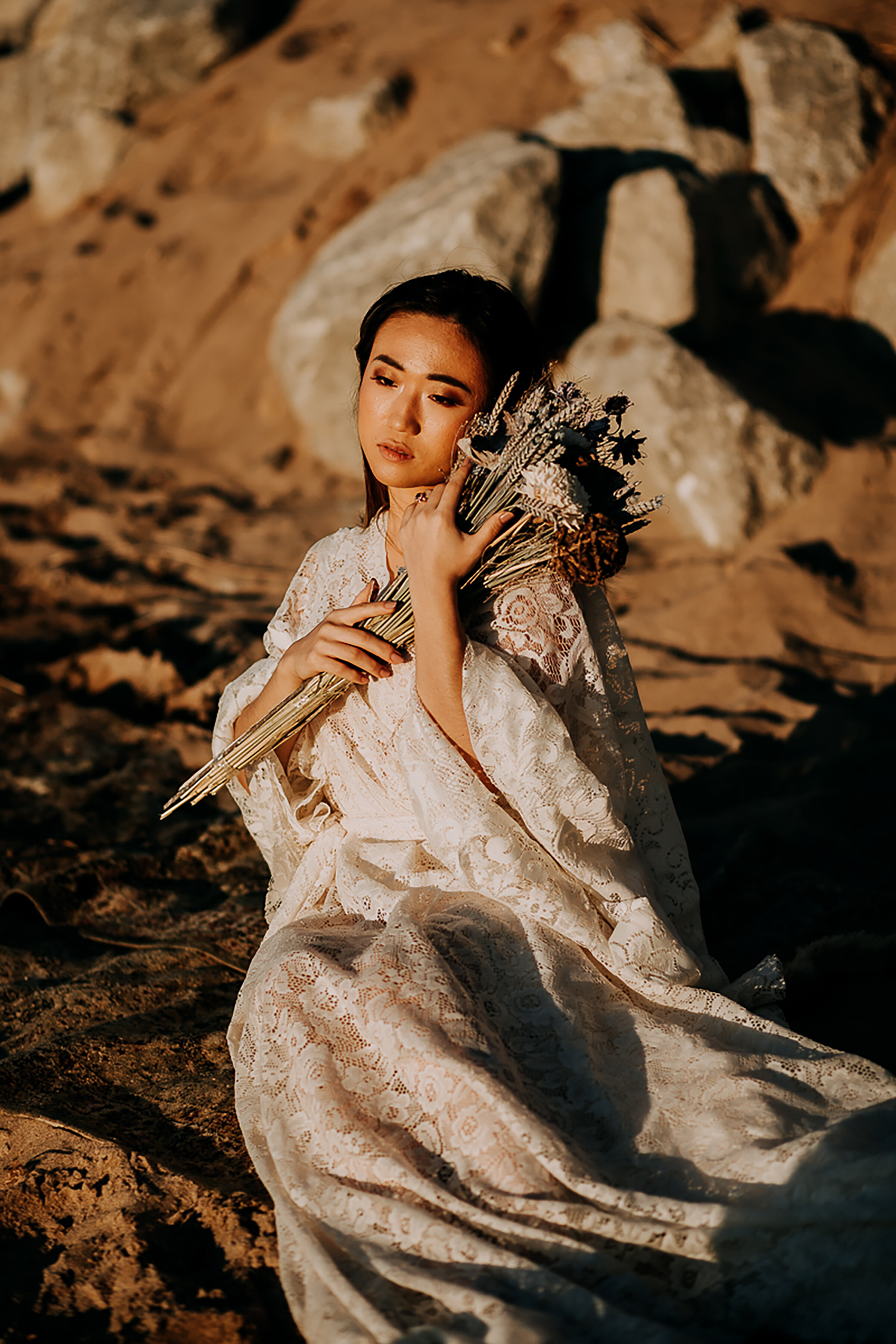  Newly eloped bohemian bride poses for Kindred &amp; Co. Photography on the rocky coastline of Indiana Dunes National Lakeshore. long lace bohemian flowy wedding dress, long lace bohemian elopement dress, bohemian dried floral bouquet, styled elopeme
