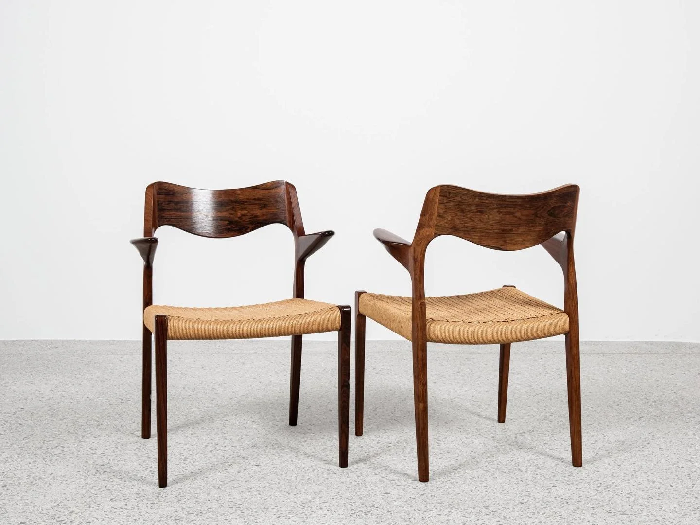 Midcentury Danish pair of chairs with armrests in rosewood model 55 by Niels Otto M&oslash;ller

There is a logo by the manufacturer under the seat. It is model 55. Rare to find, especially in rosewood! It is basically model 71, but with armrests. Th