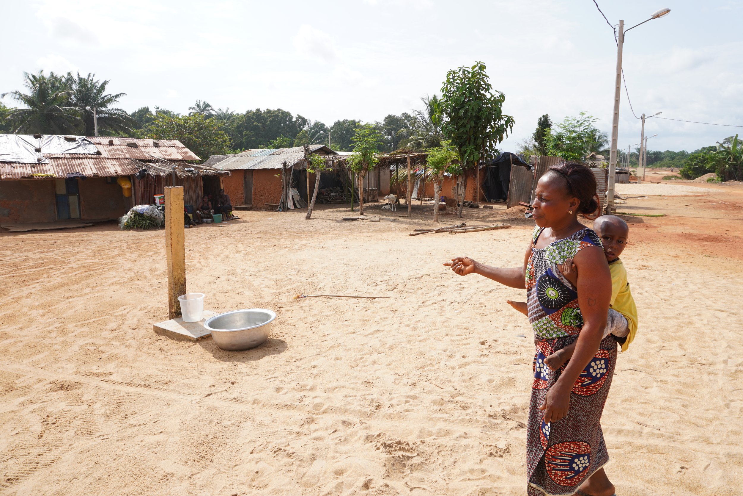  Charlotte Wadé, femme du chef de tribu et présidente de l’Association de femmes pour le développement de Dawa (AFDD), montre le robinet offert par la CEM. Ce robinet est lié à un château d’eau qui se trouve à l’entrée du village, près de la grande r
