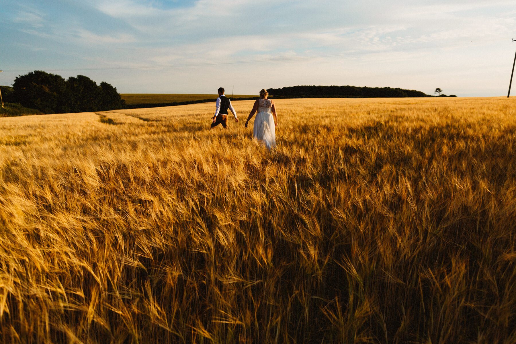 Image of couple walking through fields by Hampshire Wedding Photographer Jason Williams Photography