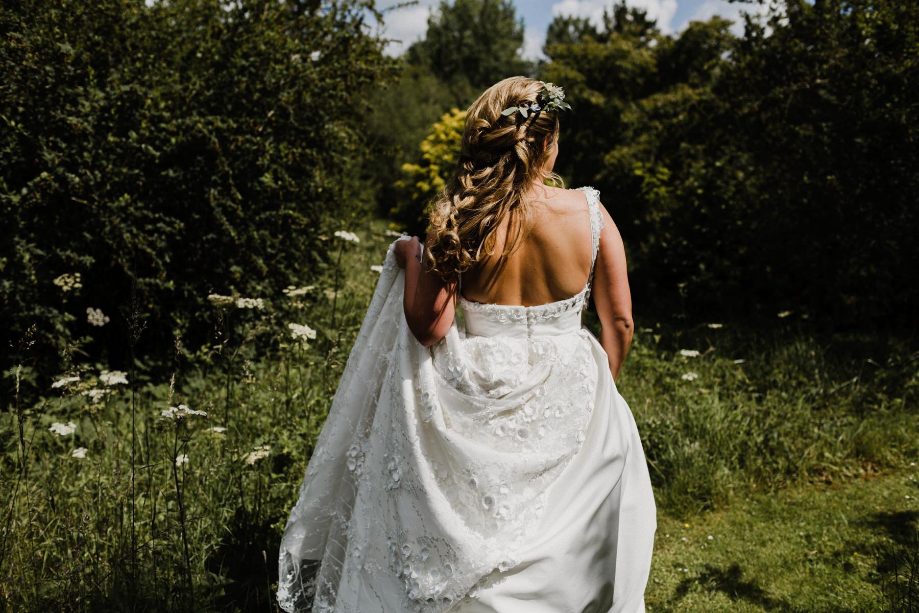 Bride walking through the fields to her wedding ceremony at Kingsettle Stud wedding venue