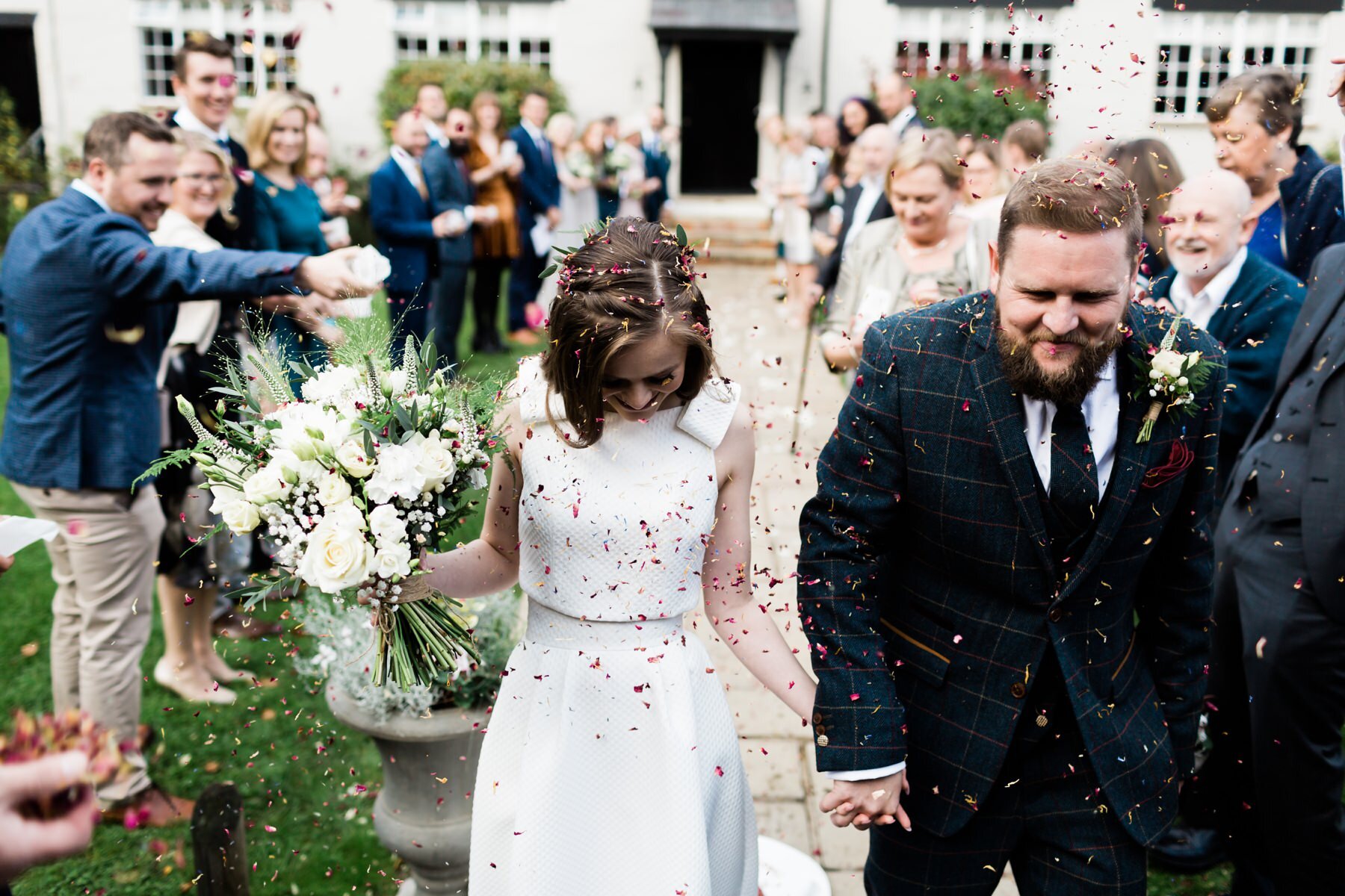 A bride and grown have confetti thrown over them at Burley Manor in the New Forest