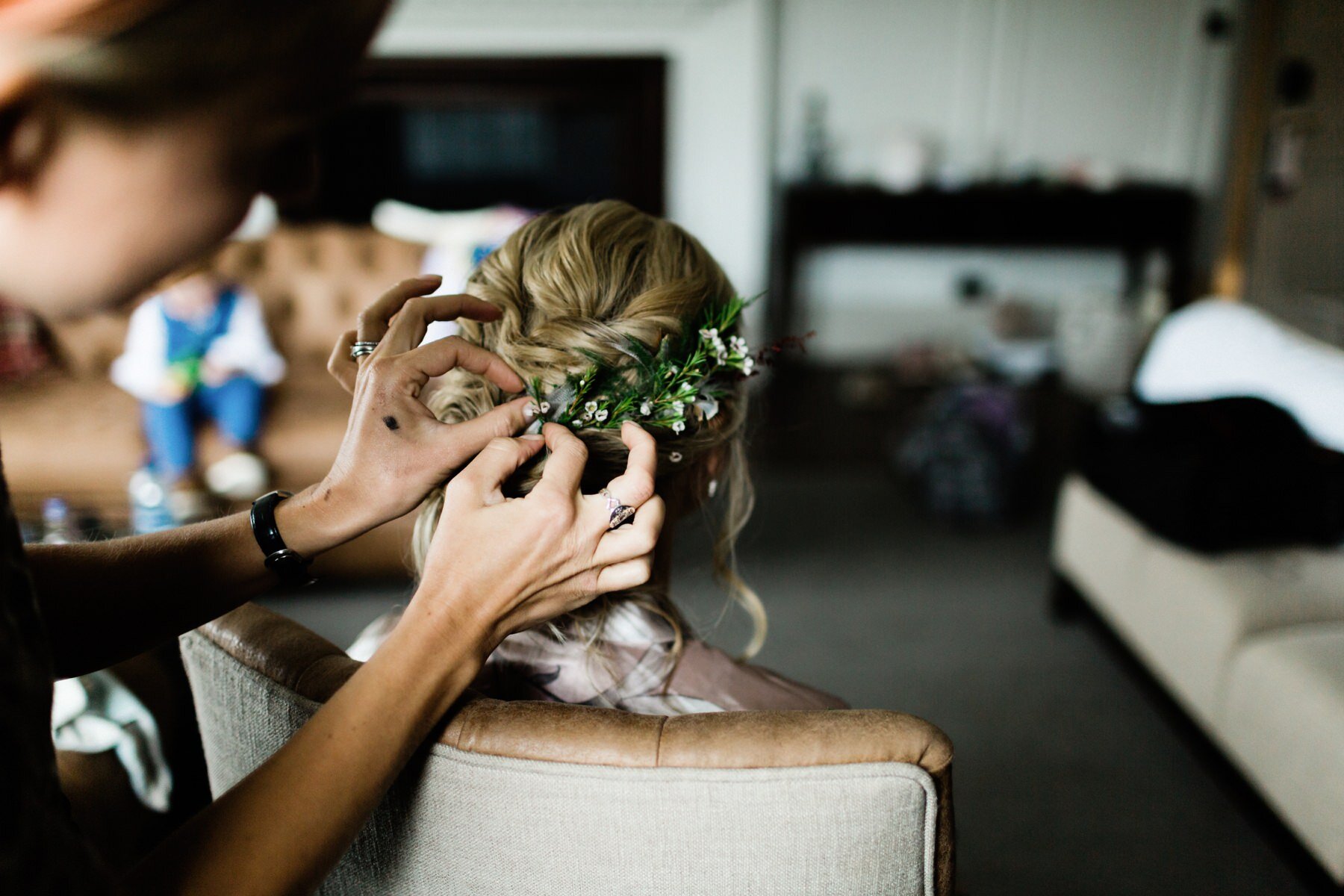 A bride having her hair styled with flower details at Horsely Towers wedding venue in Surrey.