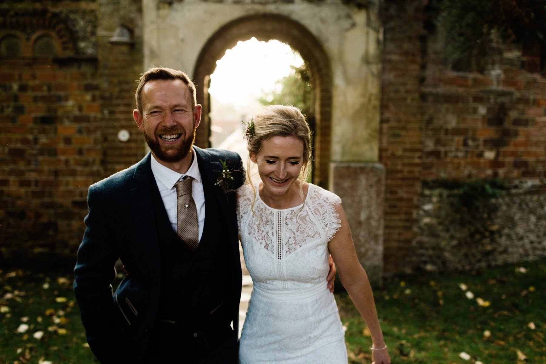 A bride and groom walk together laughing at Horsely Towers wedding venue in Surrey.