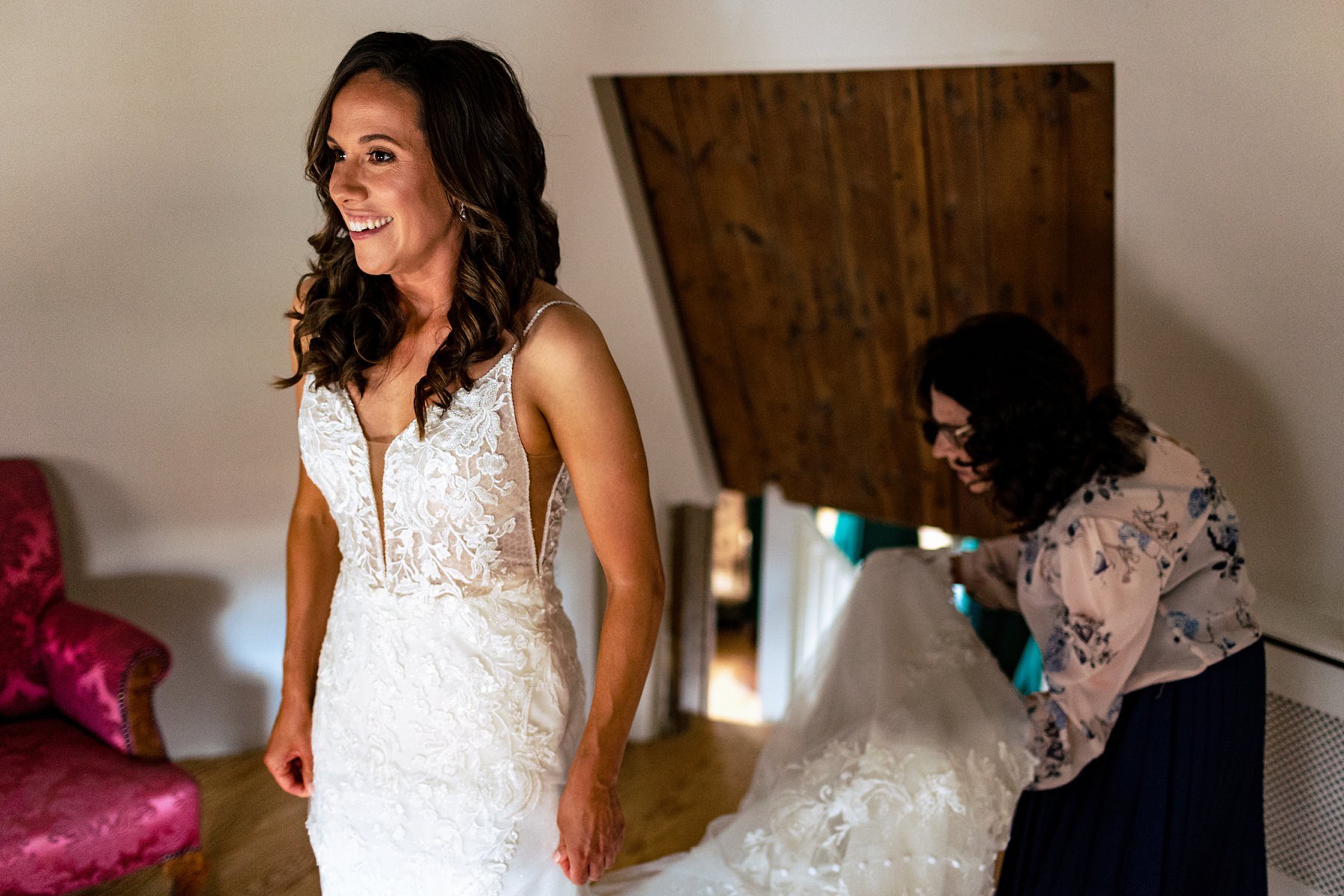 A bride smiling after she just got into her sleeveless wedding dress.