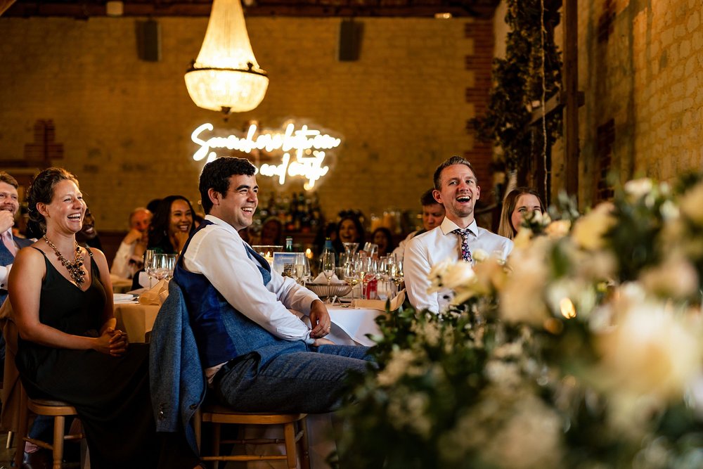 Wedding guests laugh during the speeches of a wedding reception at Bury Court Barn