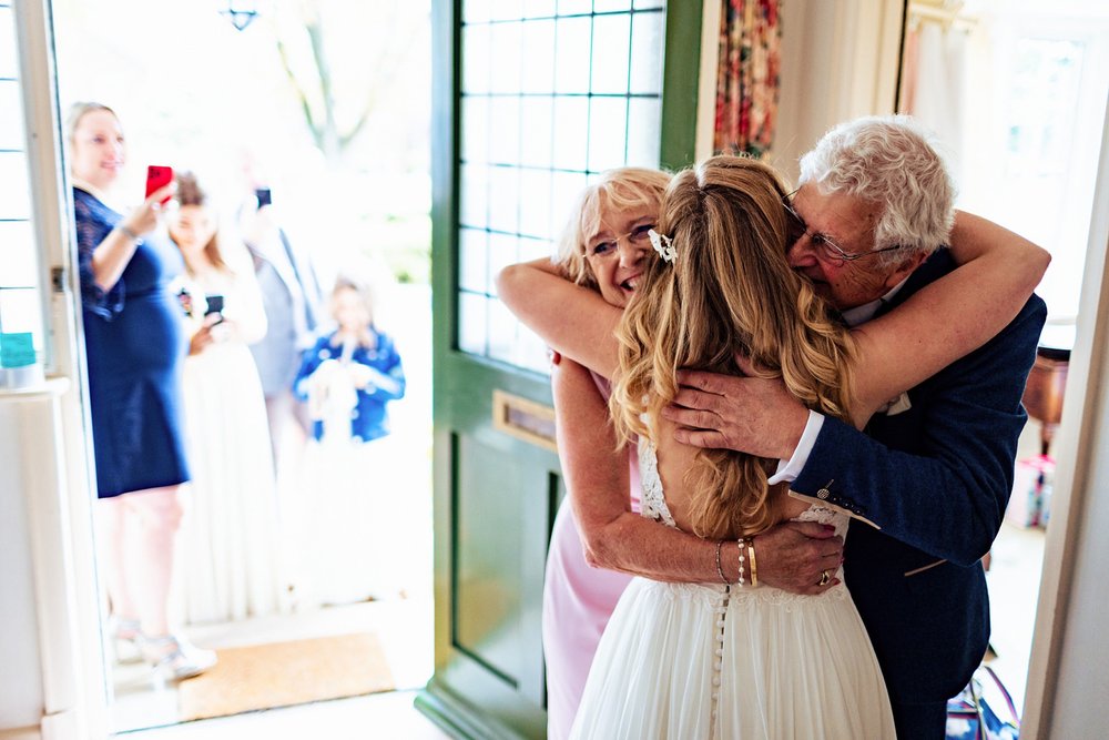 A bride hugs her mum and dad before leaving for her wedding