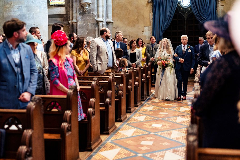 A bride walking down the aisle at St Cross Church in Winchester