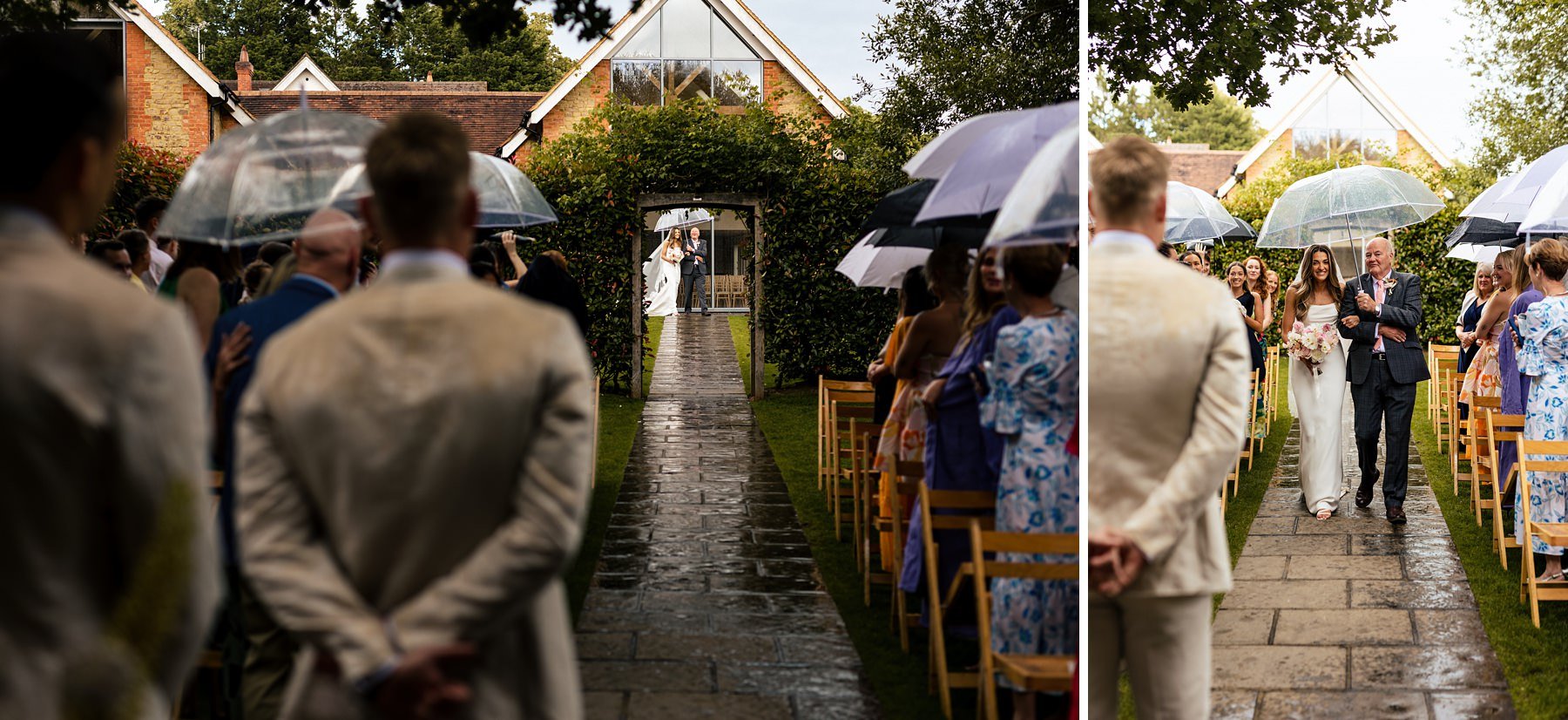 A bride walks down the aisle under an umbrella at her outdoors wedding, accompanied by her father. Some of the guests have umbrellas up also. 