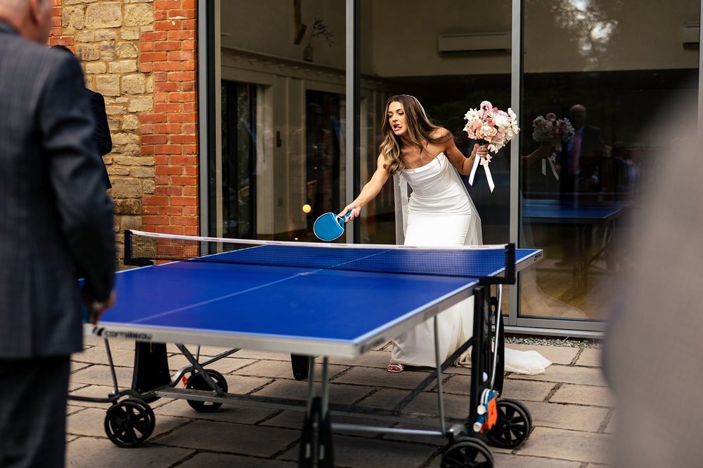 A bride plays table tennis at her wedding at Millbridge Court
