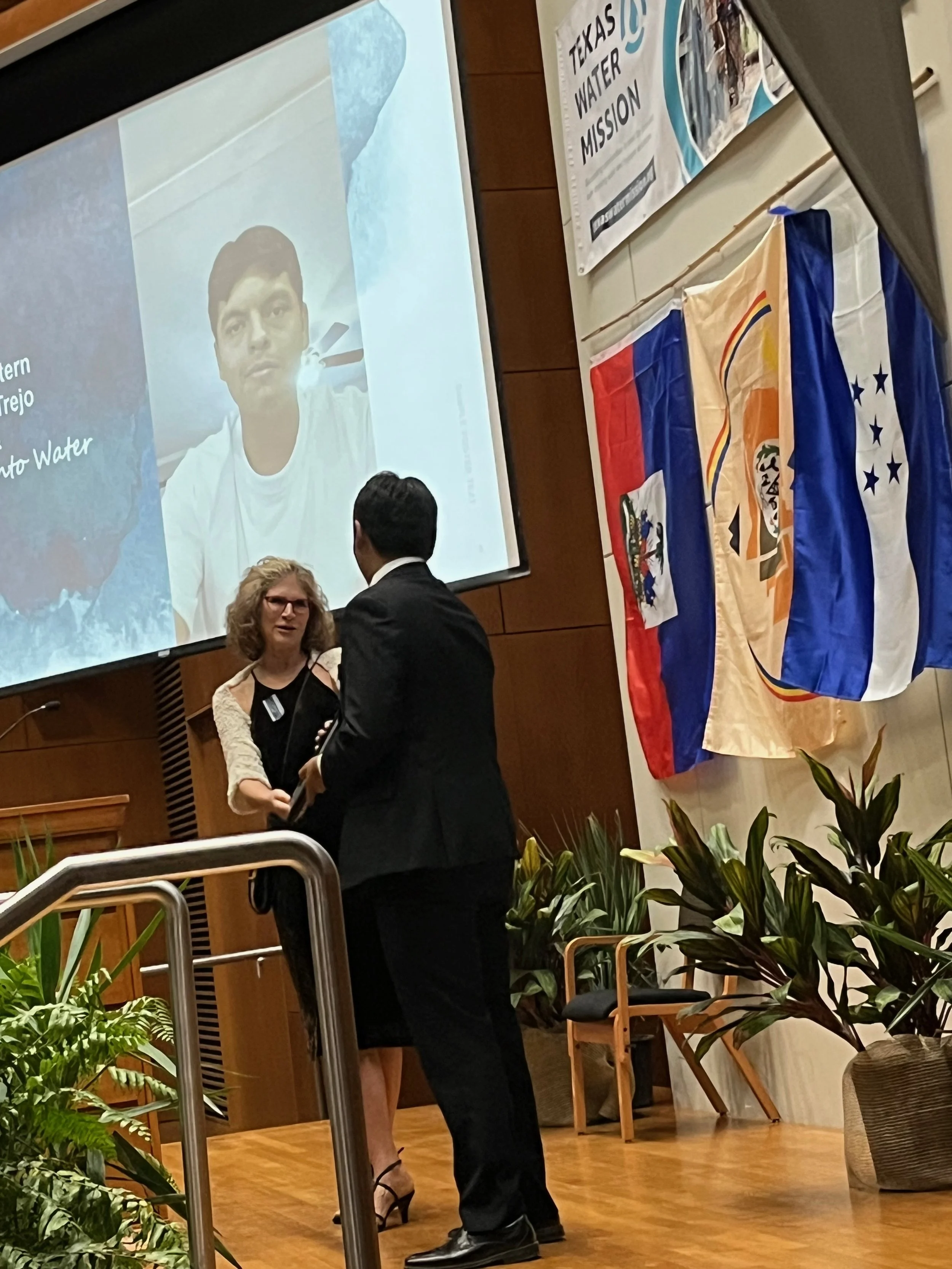 Linda handing Eber plaque in front of screen.jpeg