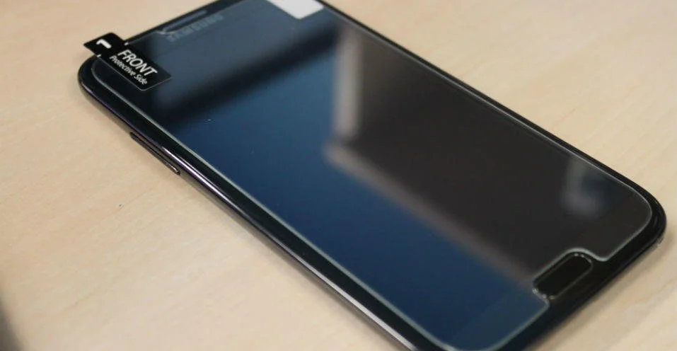 Screen protector installation on a mobile device with the front label facing up